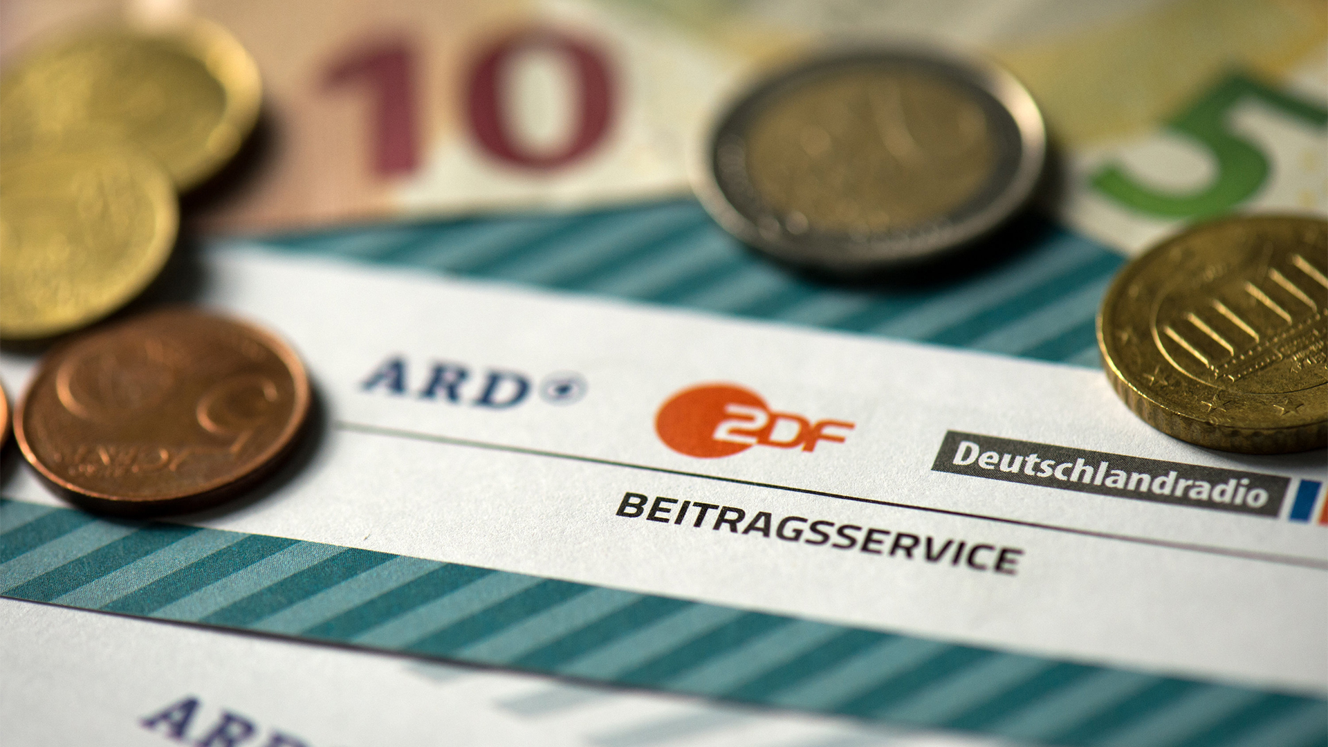 Münzgeld liegt auf Formularen für den Rundfunkbeitrag von ARD, ZDF und Deutschlandradio | dpa