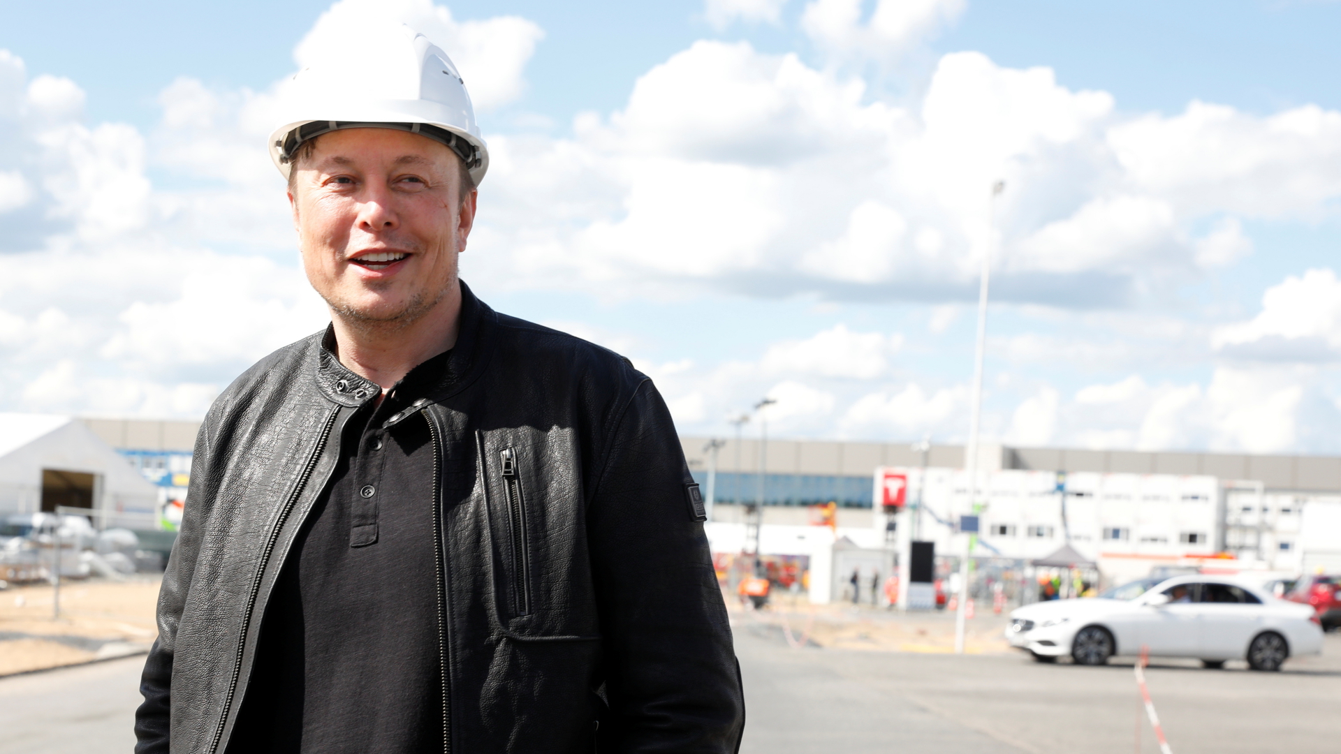 Elon Musk steht am Tesla-Gelände in Grünheide und hält einen Baumhelm in der Hand | REUTERS