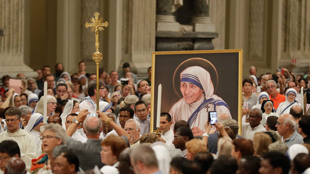 Ein Bild von Mutter Teresa wird zwischen vielen Menschen getragen.