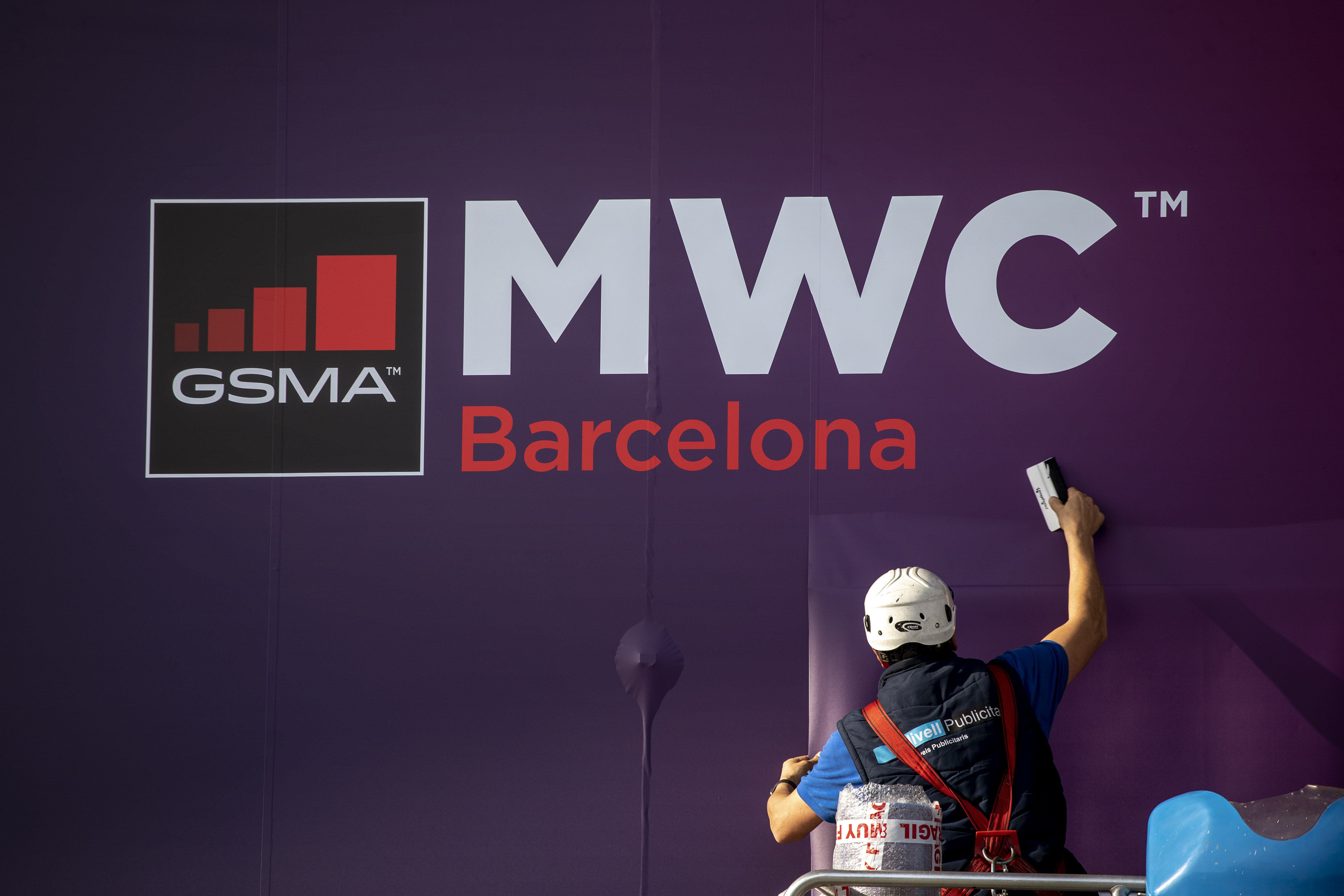 Mann steht vor einem Plakat mit Werbung für den Mobile World Congress in Barcelona | dpa
