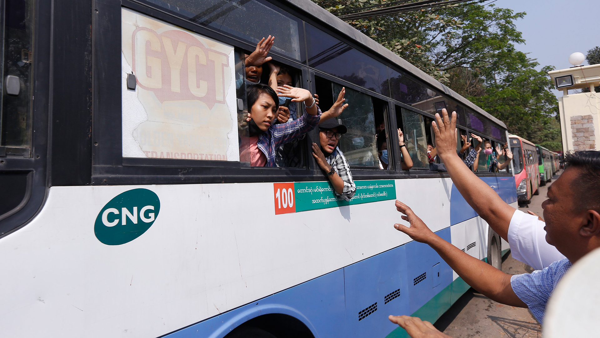 Festgenommene Demonstranten winken in Yangon Menschen zu, während sie in einem Bus sitzen. | AP