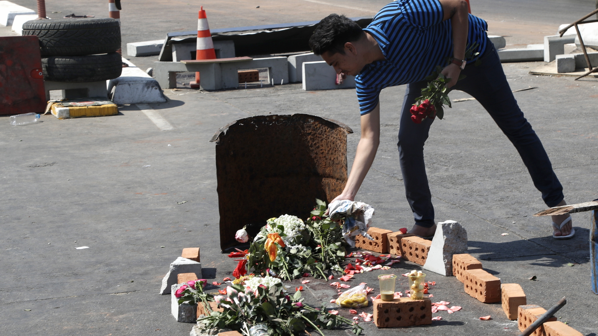 Mann legt Blumen auf die Straße zum Gedenken an ein Opfer | EPA