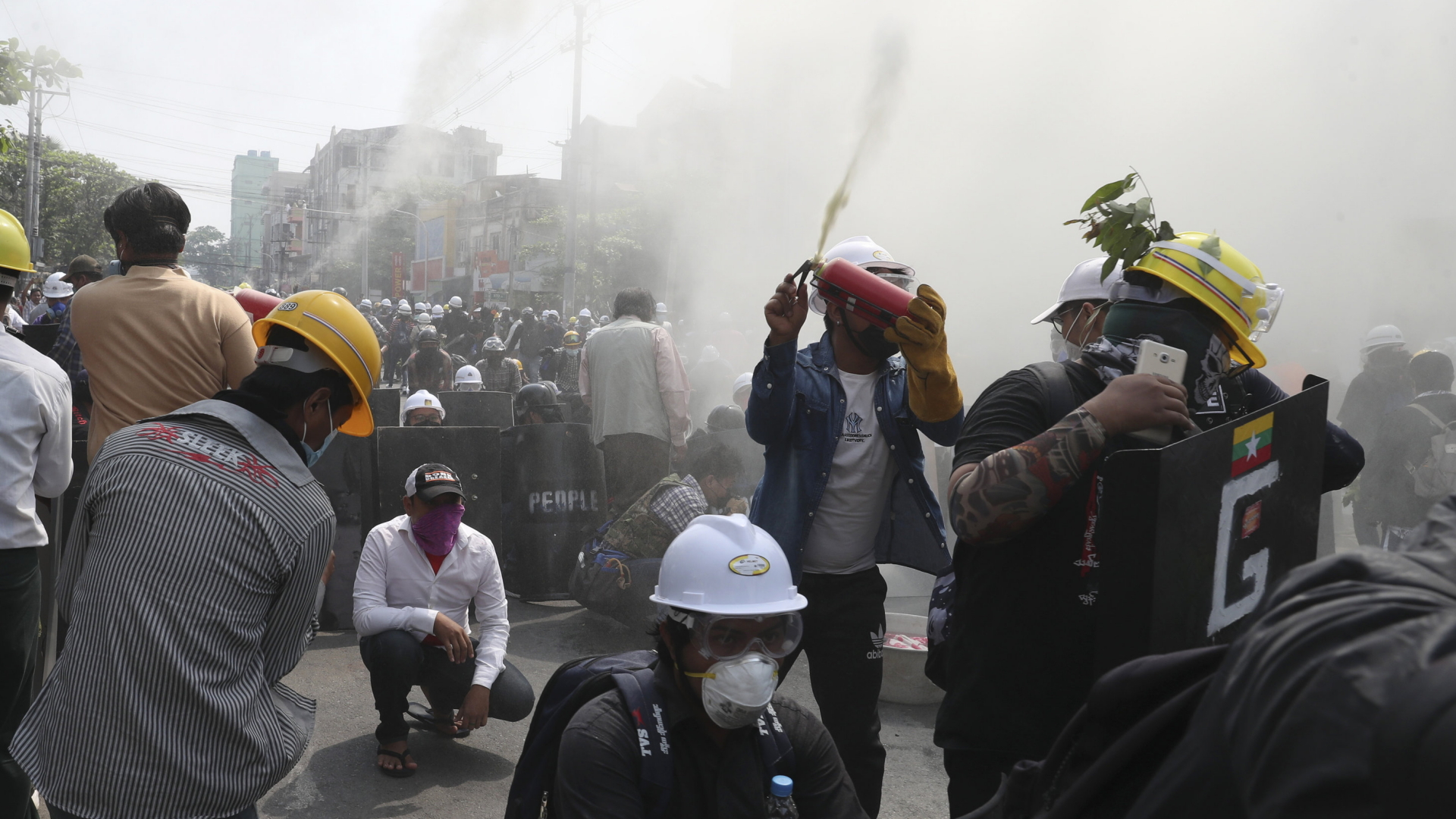 Demonstranten in der Stadt Mandalay gehen mit Feuerlöschern gegen Tränengasgranaten vor. | AP
