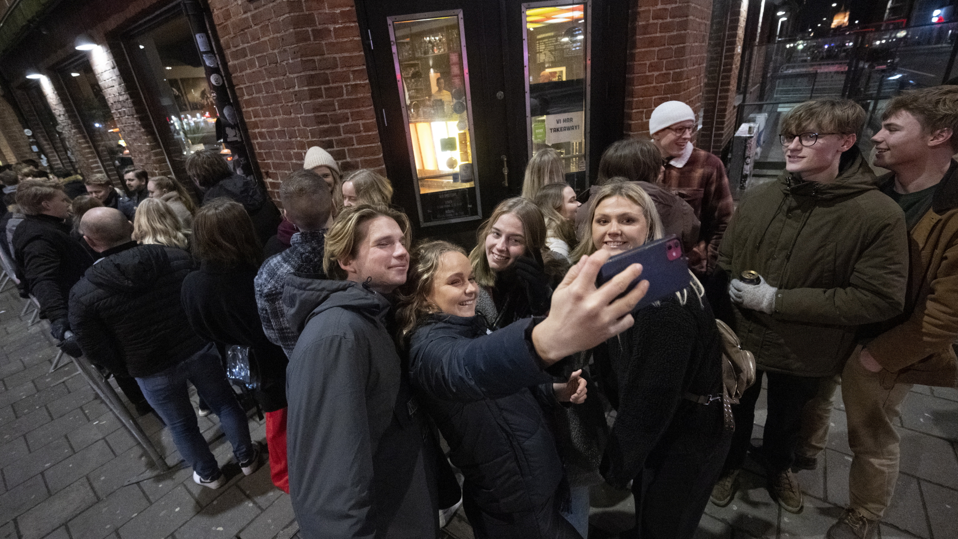 Menschen stehen in einer Schlange vor einem Nachtclub und machen ein Selfie in Malmö, Schweden. | EPA