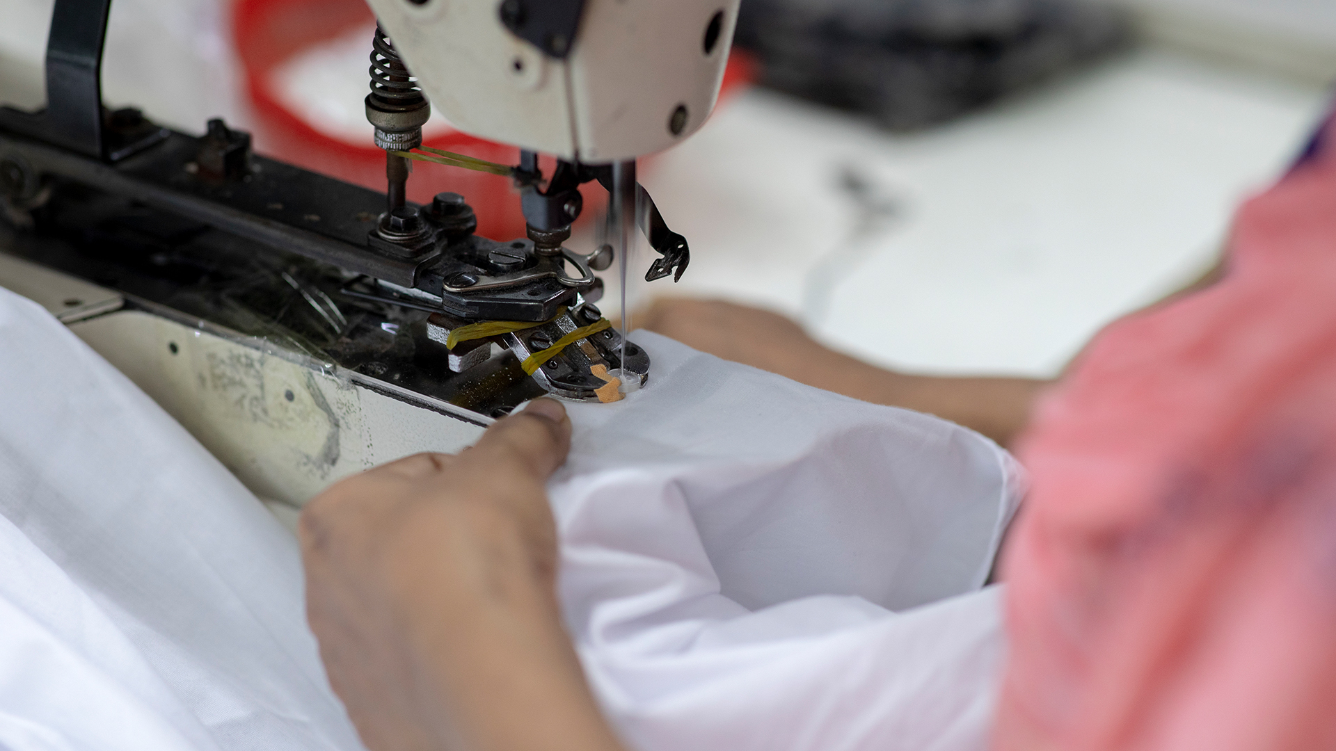 Eine Frau arbeitet in einer Textilfabrik an einer Nähmaschine. | picture alliance/dpa