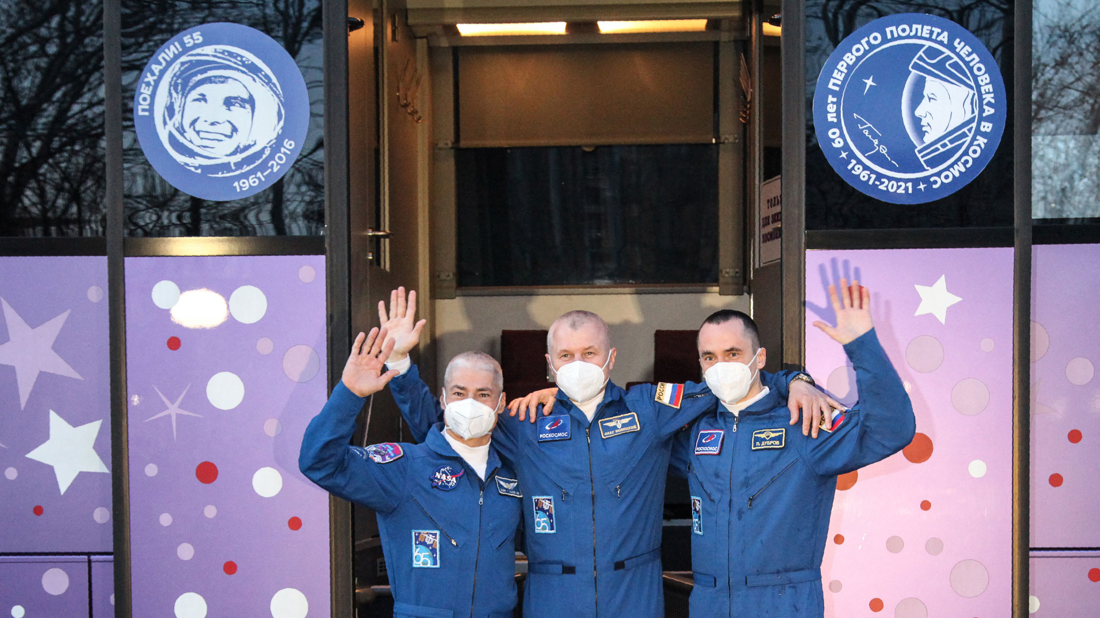 Ein Astronaut und zwei Kosmonauten winken zum Abschied. | AFP