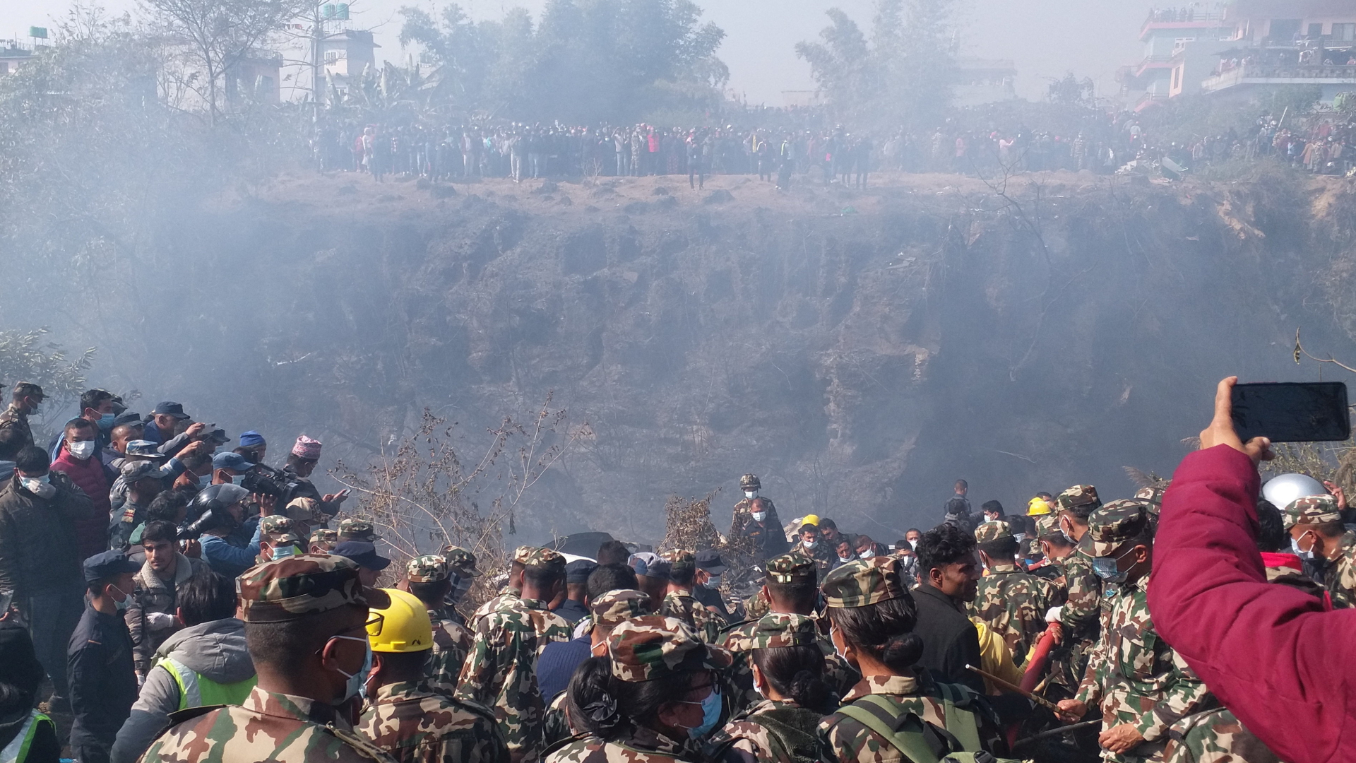 Menschenmengen versammeln sich, während Rettungsteams an der Absturzstelle eines Flugzeugs die Leichen bergen. | via REUTERS