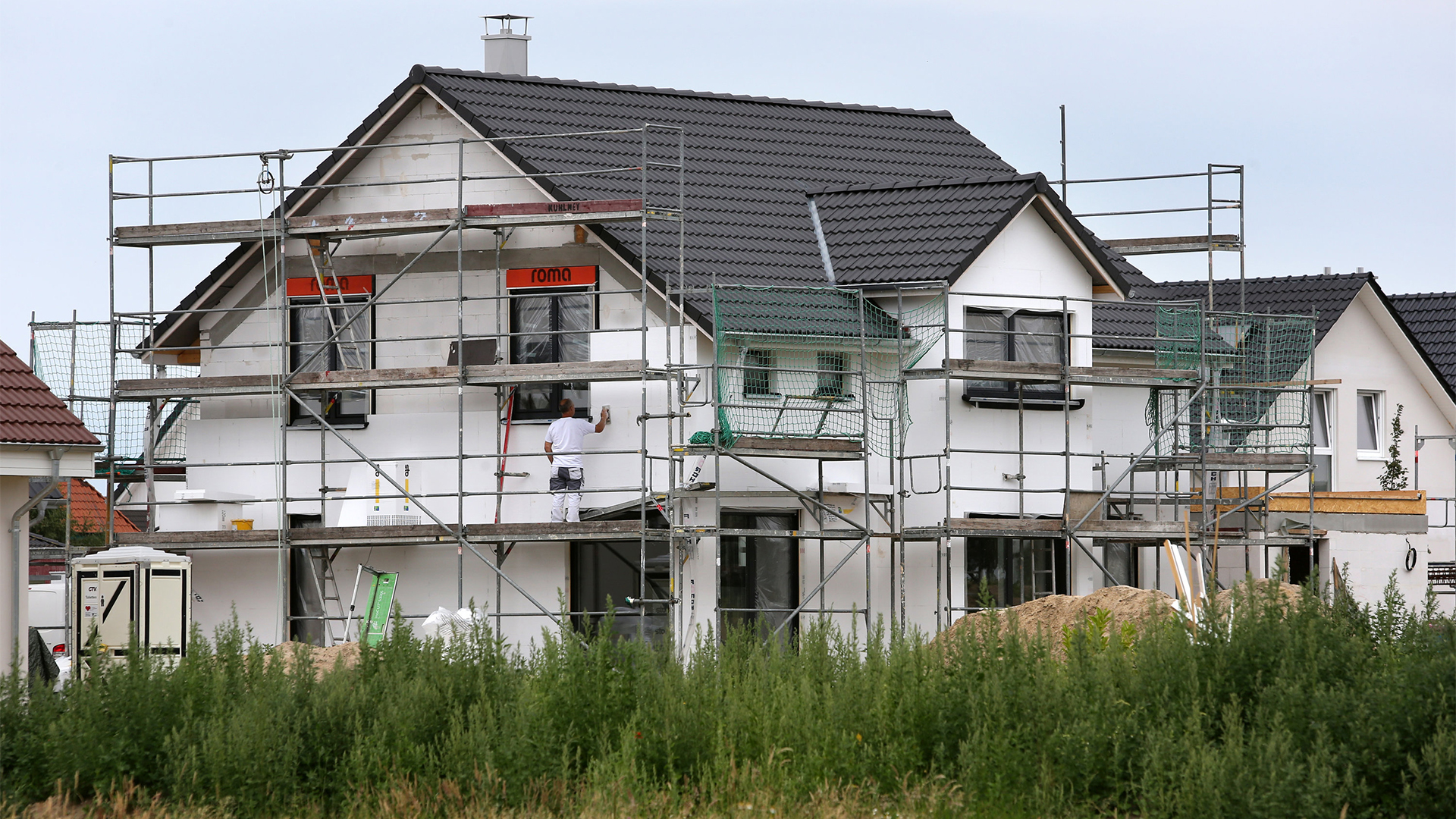 Bauarbeiter arbeiten an der  Fertigstellung von Einfamilienhäusern | dpa