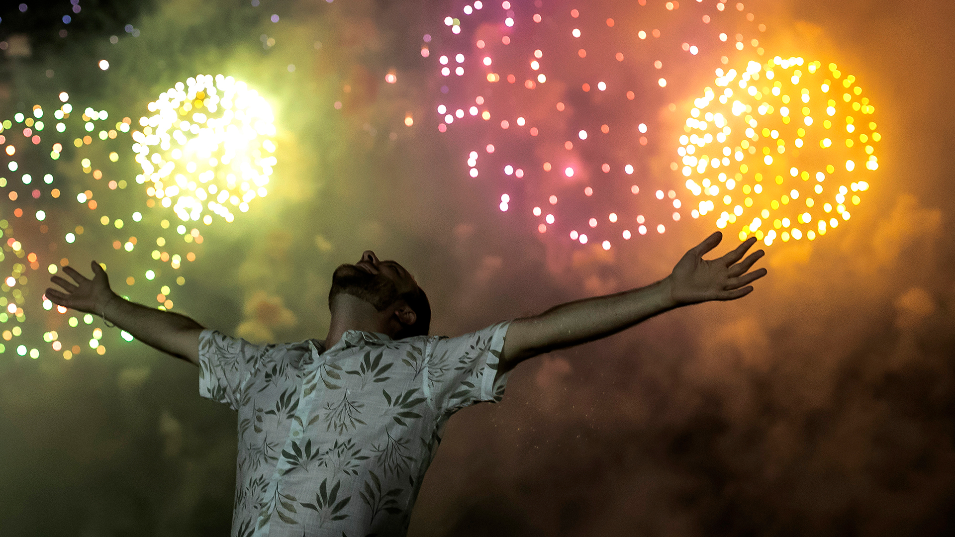 Ein Mann feiert den Beginn des neuen Jahres, während im Hintergrund ein Feuerwerk über dem Copacabana-Strand den Nachthimmel erleuchtet. | dpa