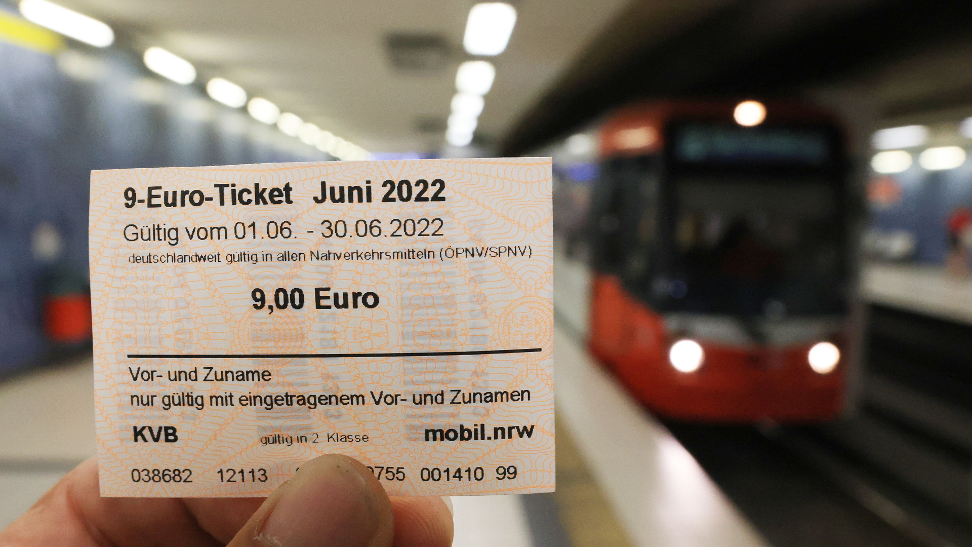 Ein Fahrgast hält in einem Kölner U-Bahnhof ein 9-Euro-Ticket in die Kamera
