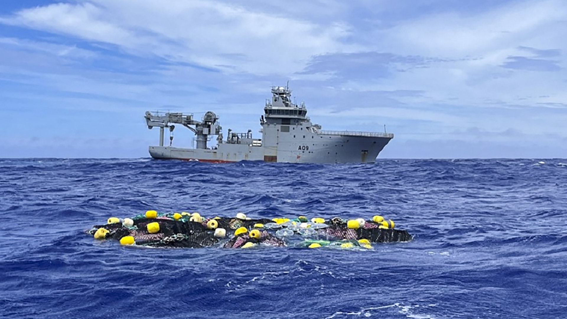 Ein Marineschiff schwimmt auf dem Meer, im Vordergrund treibt ein Fischernetz voller Drogen. | AP