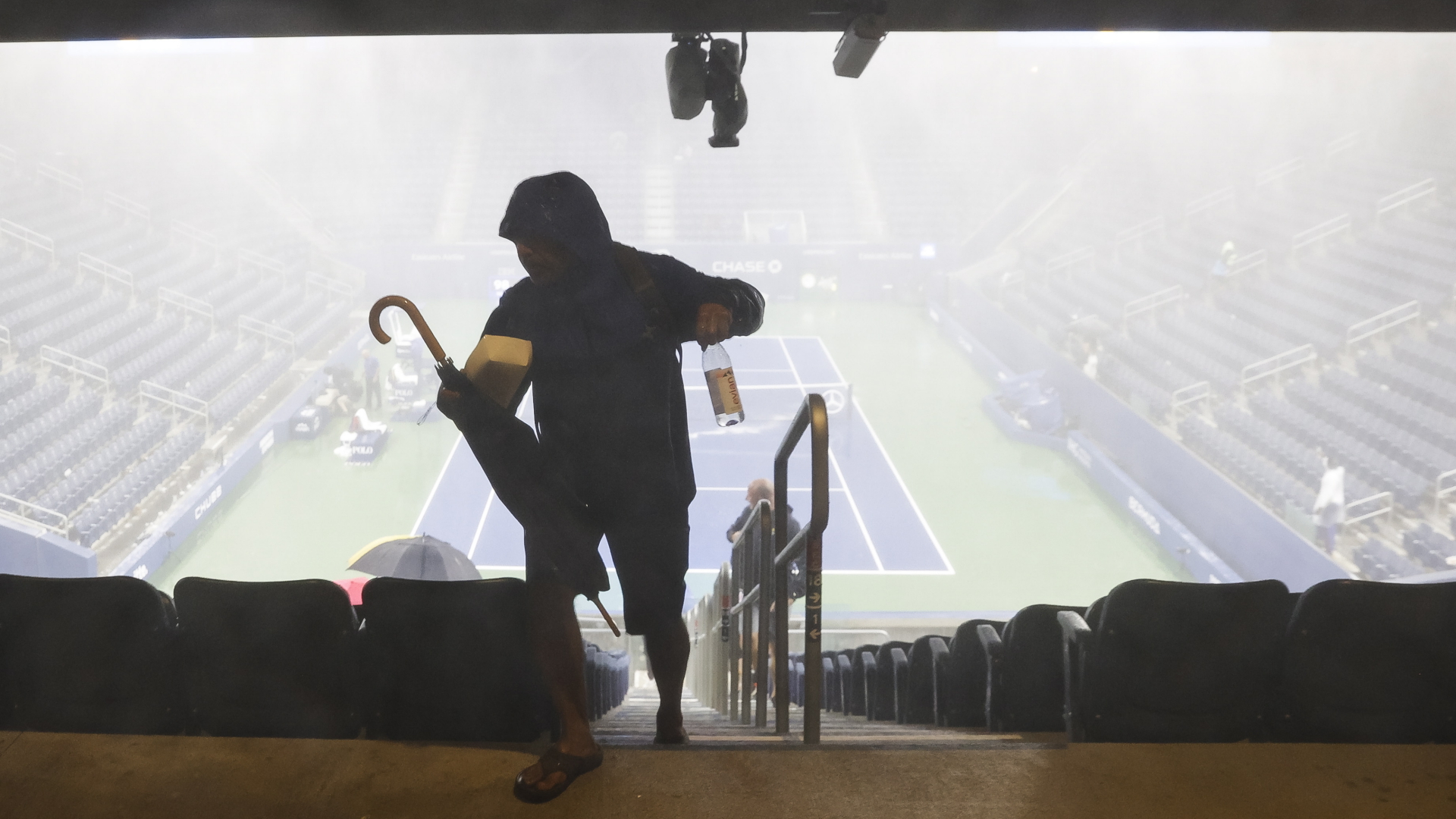 Ein Mann verlässt im Starkregen den Tennis Court bei den US Open in New York | EPA
