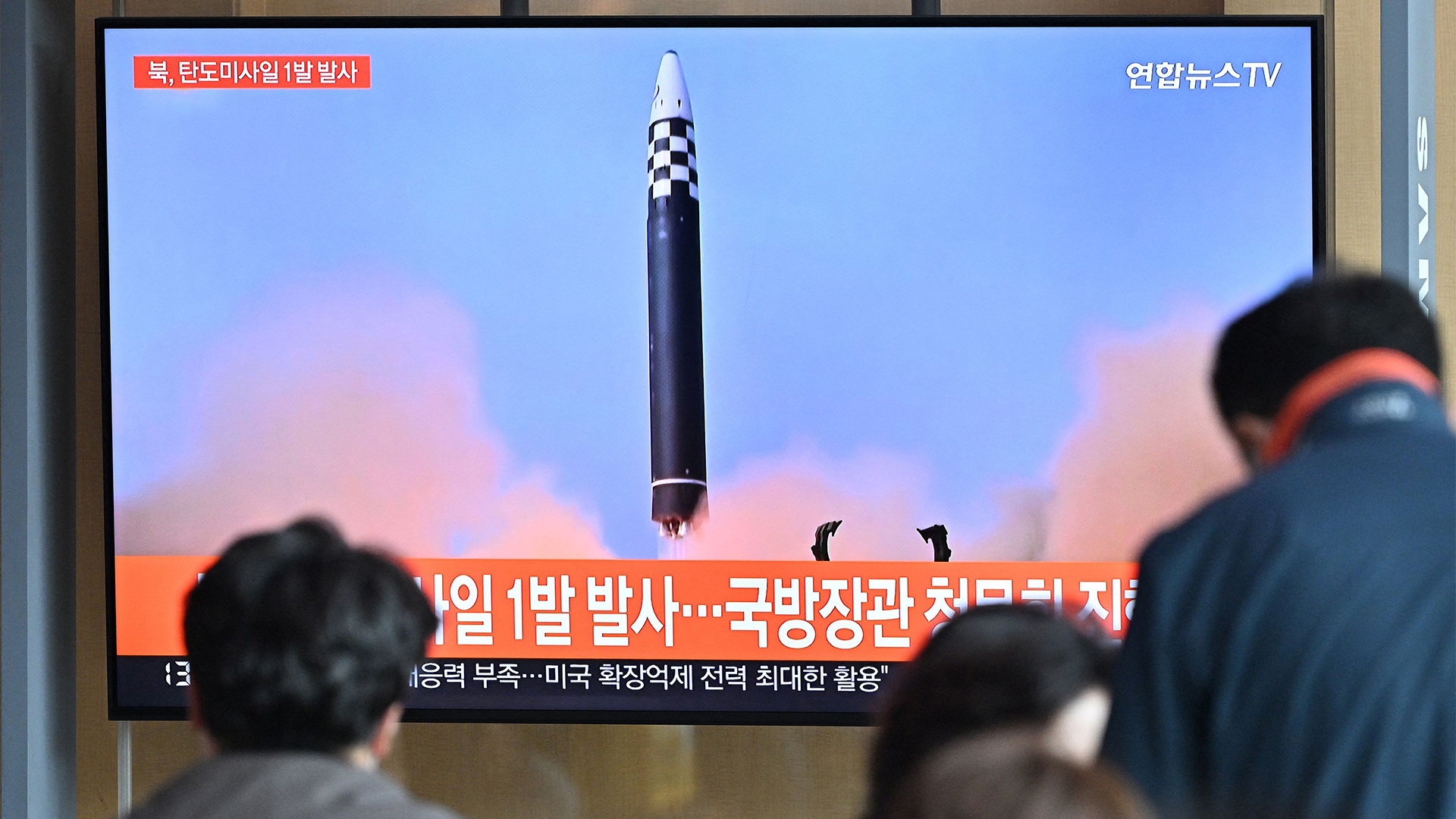 Menschen schauen in den Nachrichten einen nordkoreanischen Raketentest. | AFP