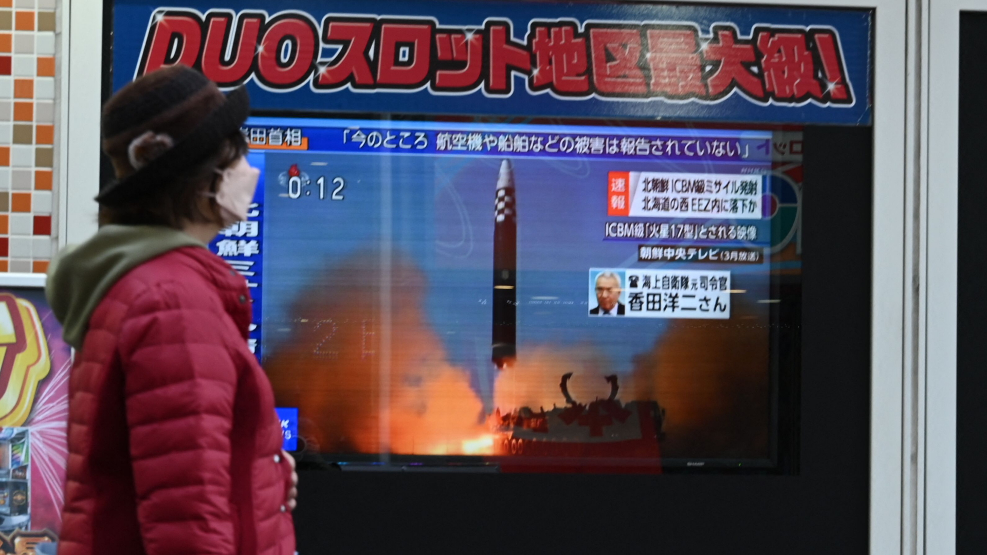 Eine Frau mit Corona-Schutzmaske läuft in Tokio an einem Schaufenster vorbei, in dem ein Fernseher Nachrichten über den mutmaßlich neuesten Raketentest Nordkoreas zeigt. | AFP
