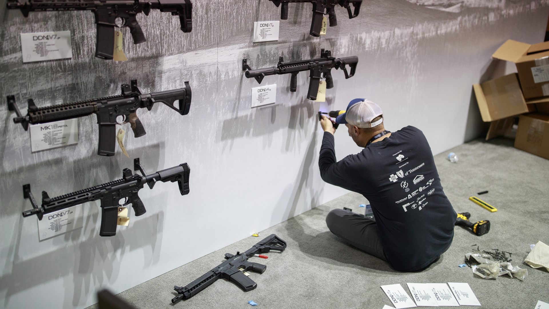 Ein Aufbauhelfer schraubt Halterungen für Modellwaffen bei der NRA-Versammlung 2019 an der Wand fest. | picture alliance / ZUMAPRESS.com