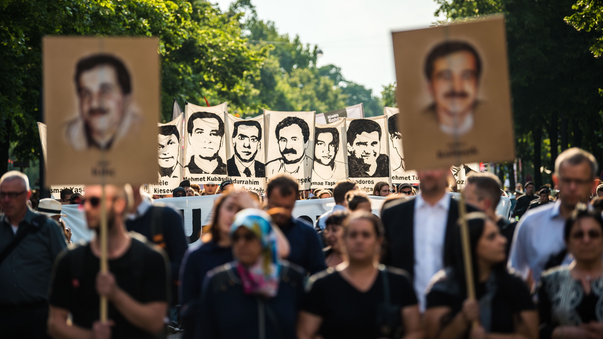Demonstranten in München halten bei einer Kundgebung Schilder mit Porträt-Abbildungen der NSU-Opfer, Archivbild | dpa