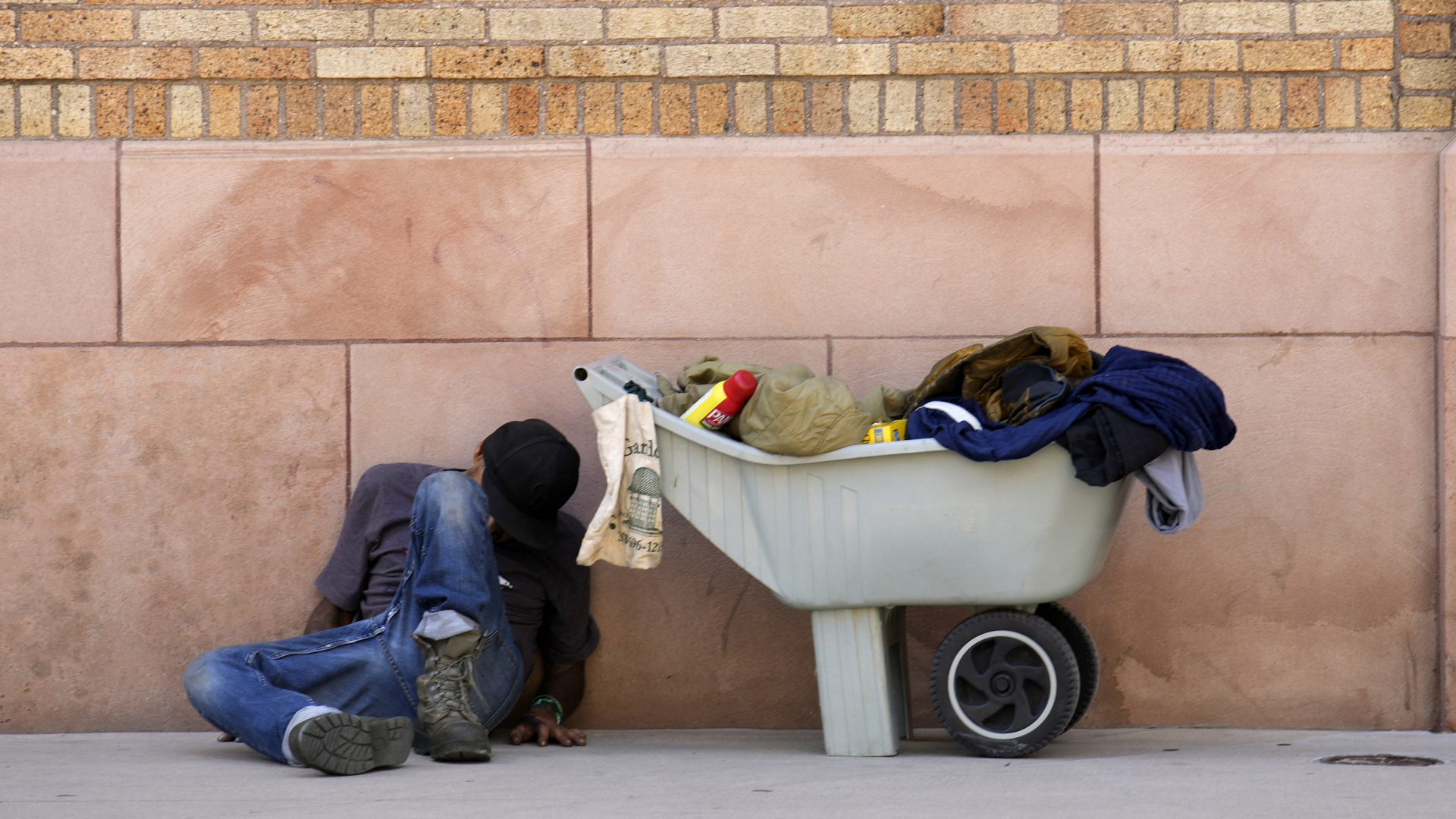 Ein Obdachloser schläft gegen eine Wand gelehnt in Denver, USA. 