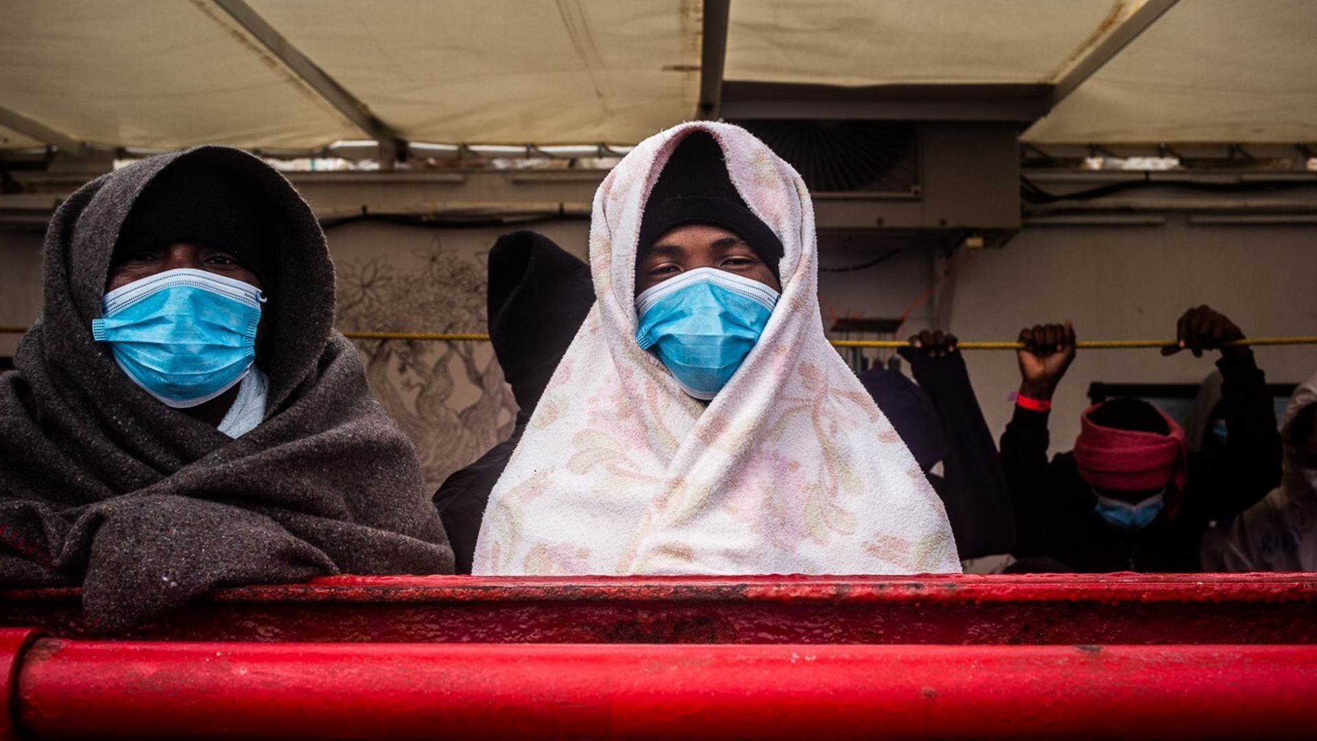 Migranten mit Mundschutz sitzen an Bord des Rettungsschiffs "Ocean Viking". | dpa