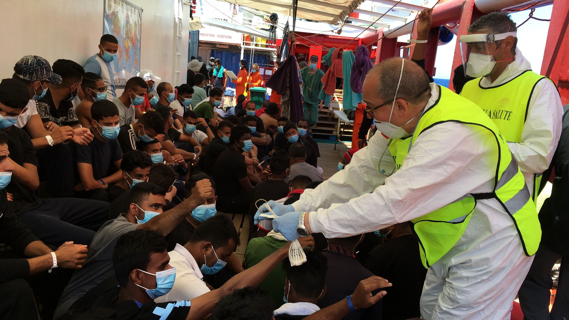 Italienische Sanitäter geben Armbänder an Migranten an Bord der "Ocean Viking" aus. | AFP