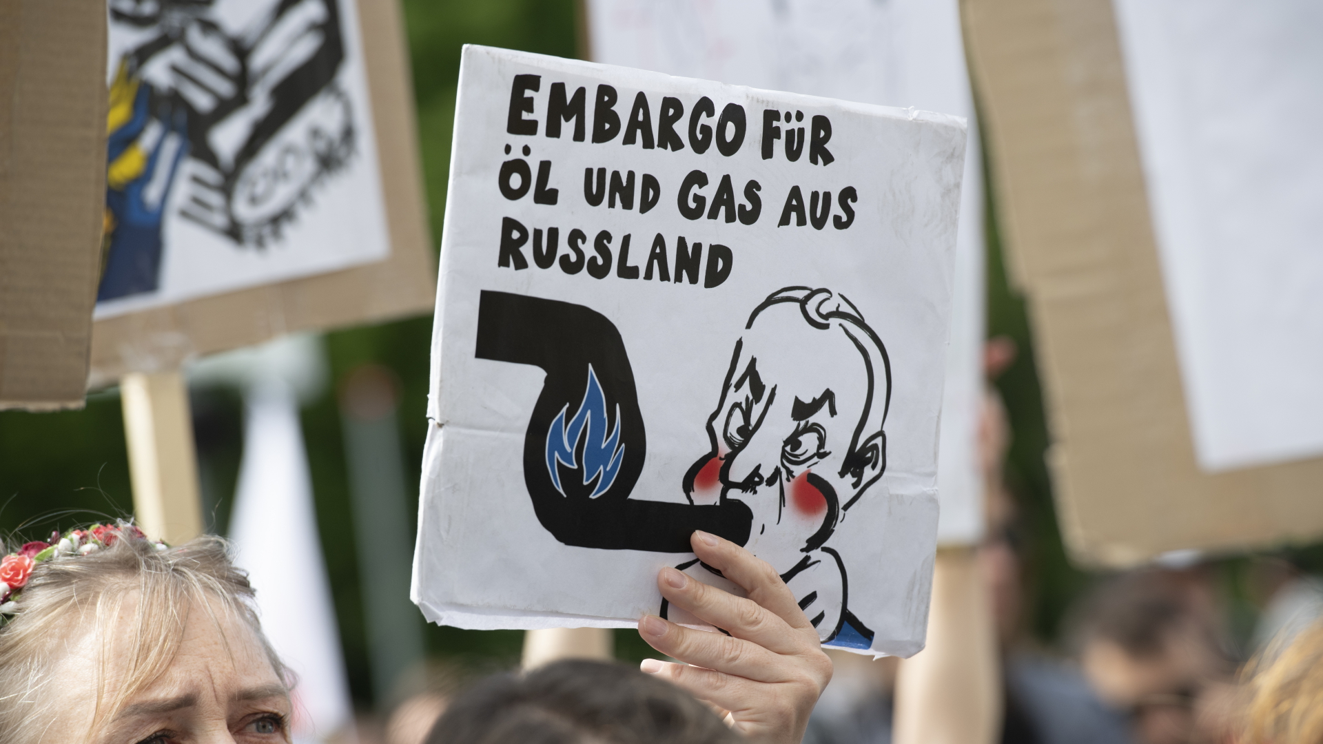 Eine Demonstrantin in Berlin hält ein Schild in die Höhe, das ein Öl- und Gas-Embargo gegen Russland fordert. | dpa