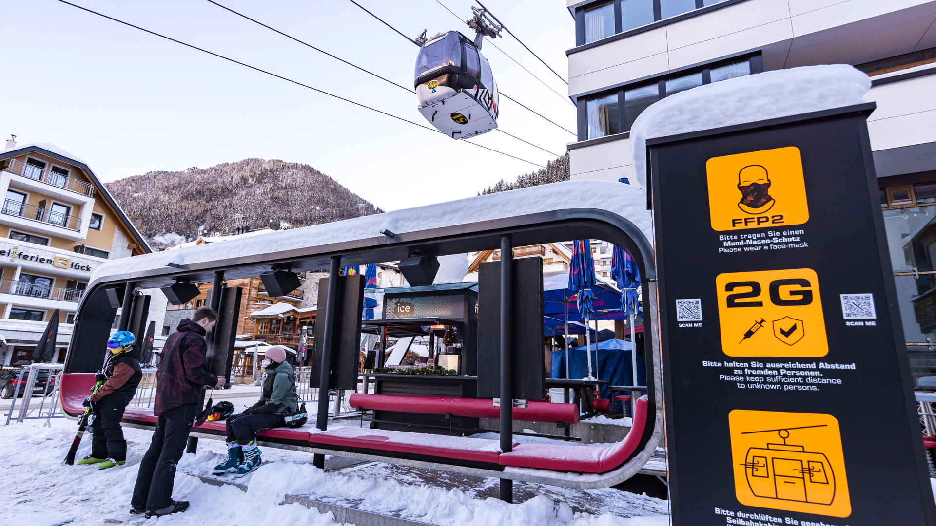 Skifahrer warten im Skigebiet um Ischgl bei der Gondel, wo Schilder auf die Corona-Regelungen hinweisen. | picture alliance/dpa/APA