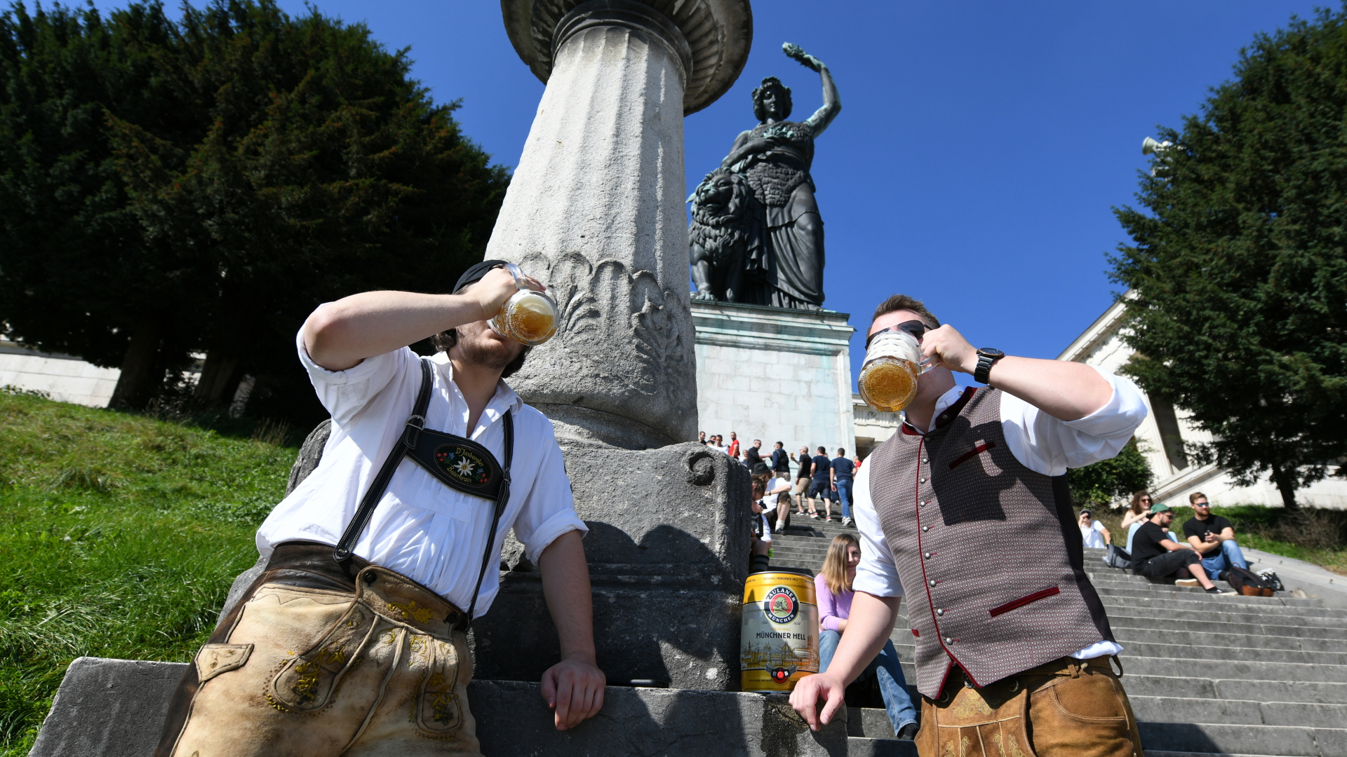 Zwei Freunde trinken pünklich um 12:00 Uhr ihr mitgebrachtes Bier auf der leeren Theresienwiese.  | dpa