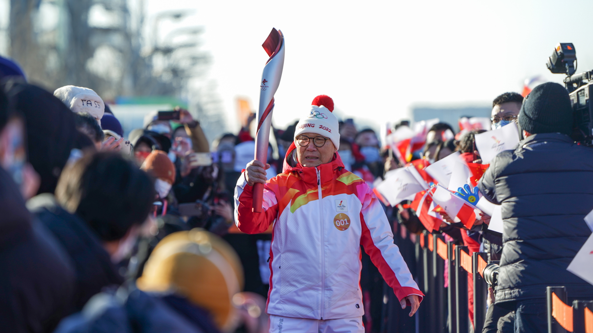 Luo Zhihan, ehemaliger Eisschnelllauf-Weltmeister, trägt die Fackel während des olympischen Fackellaufs in Peking. | dpa