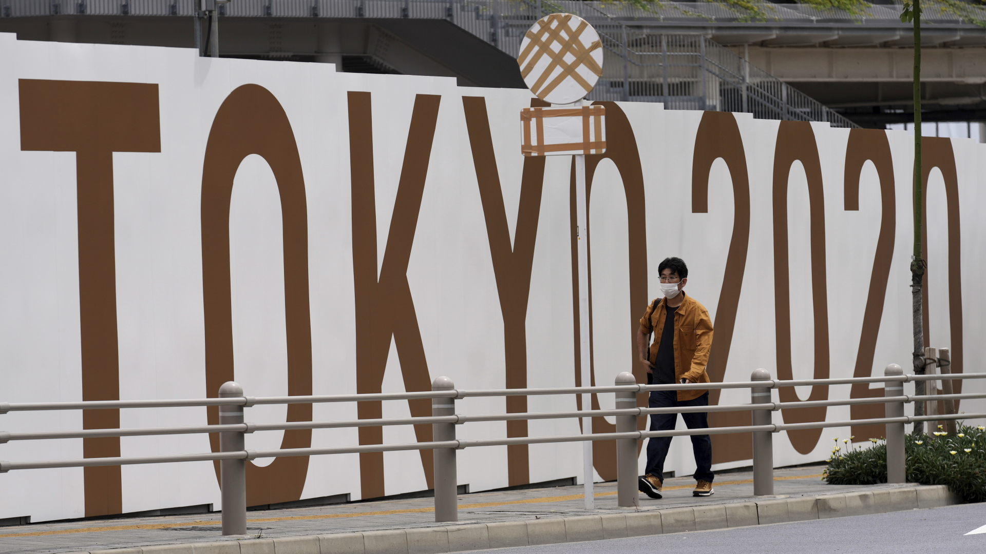 "Tokyo 2020" steht an einer Wand des Nationalstadions geschrieben, an der ein Mann vorbeigeht (Archivbild).