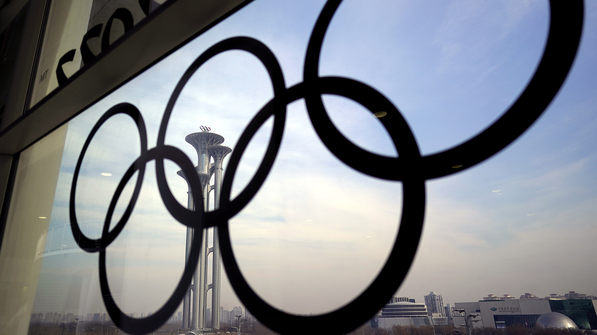 Die olympischen Ringe sind an einem Fenster im Medienzentrum der Olympischen Winterspiele in Peking zu sehen | dpa