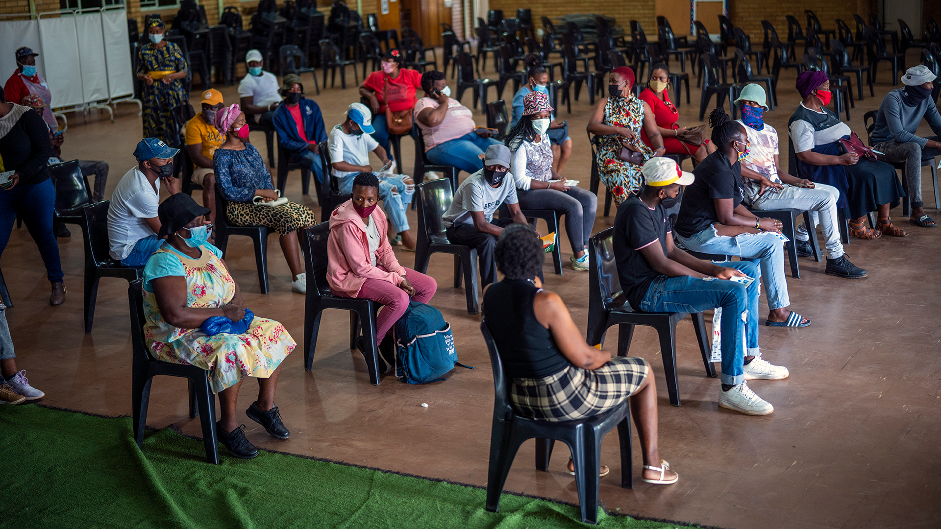 Menschen, die eine Corona-Impfung erhalten haben, warten im Mehrzweckzentrum von Orange Farm auf die Bearbeitung ihres Impfausweises. | picture alliance/dpa/AP