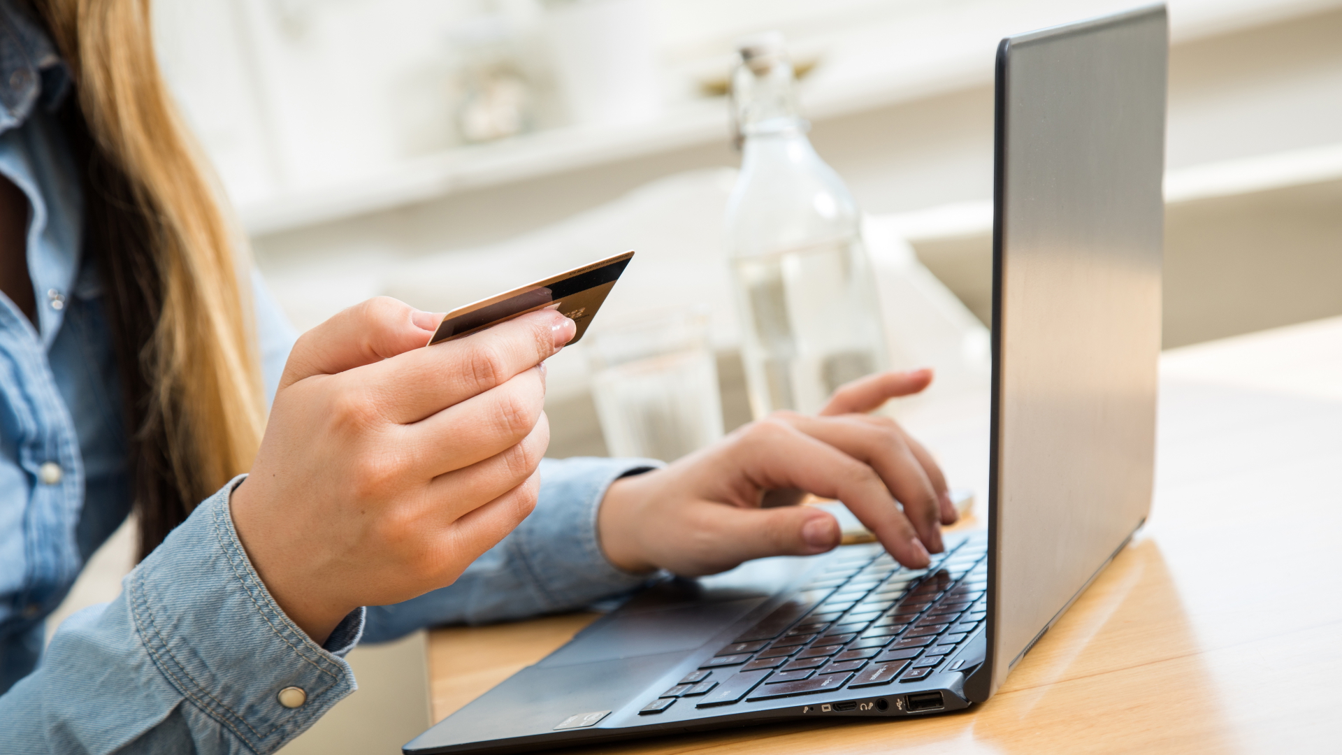 Eine Frau tippt an einem Laptop Daten ihrer Kreditkarte ein