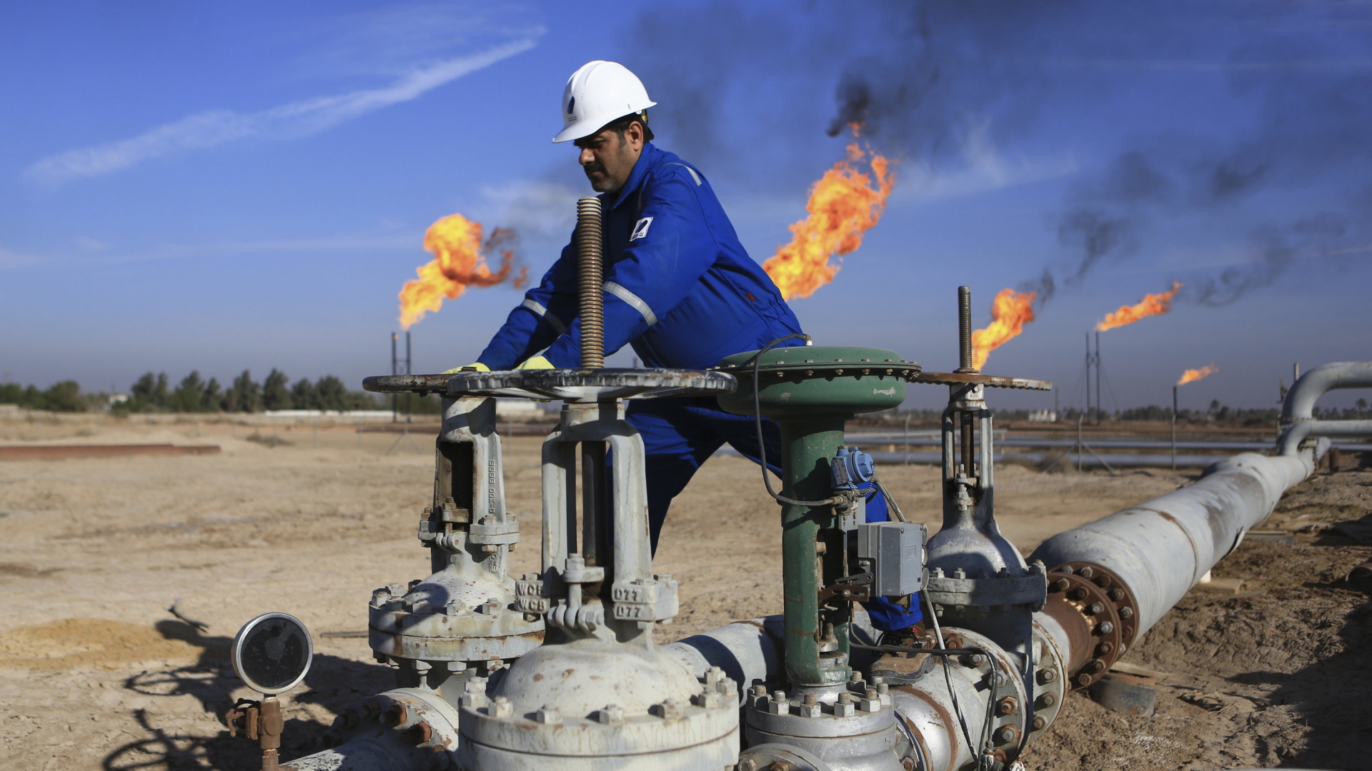 Ein Arbeiter greift an Ventile einer Ölleitung auf dem Ölfeld Nihran Bin Omar im Irak | Bildquelle: dpa