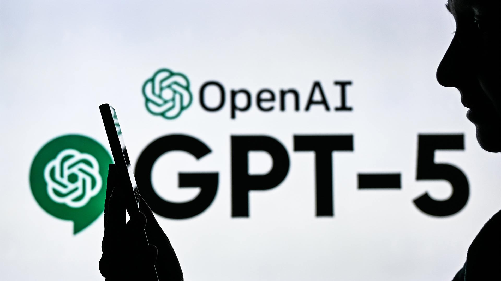 Eine Frau mit Smartphone steht vor dem Logo von OpenAI und Chat GPT-5.