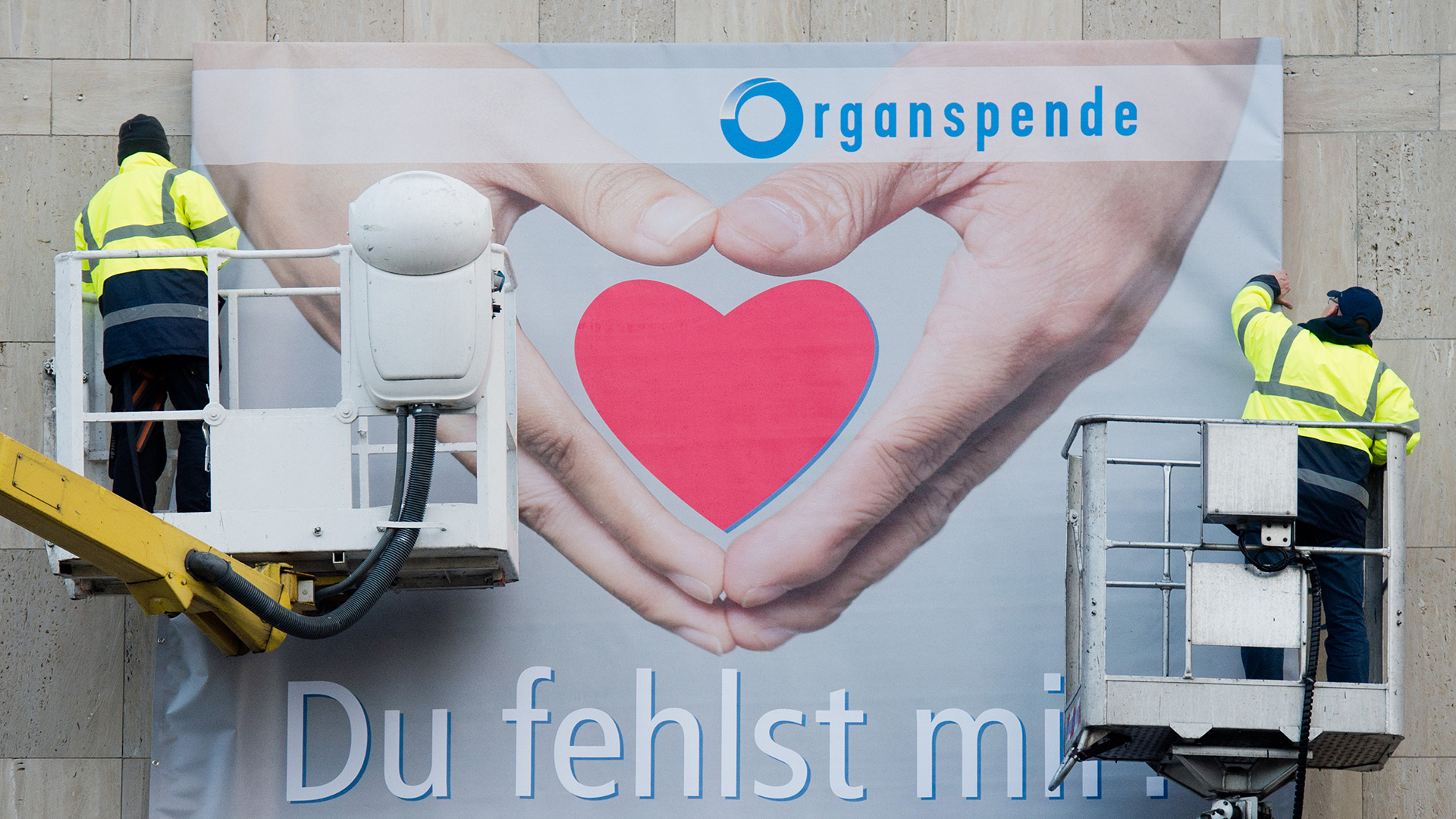 Arbeiter montieren ein Plakat zum Thema Organspende | picture alliance / dpa