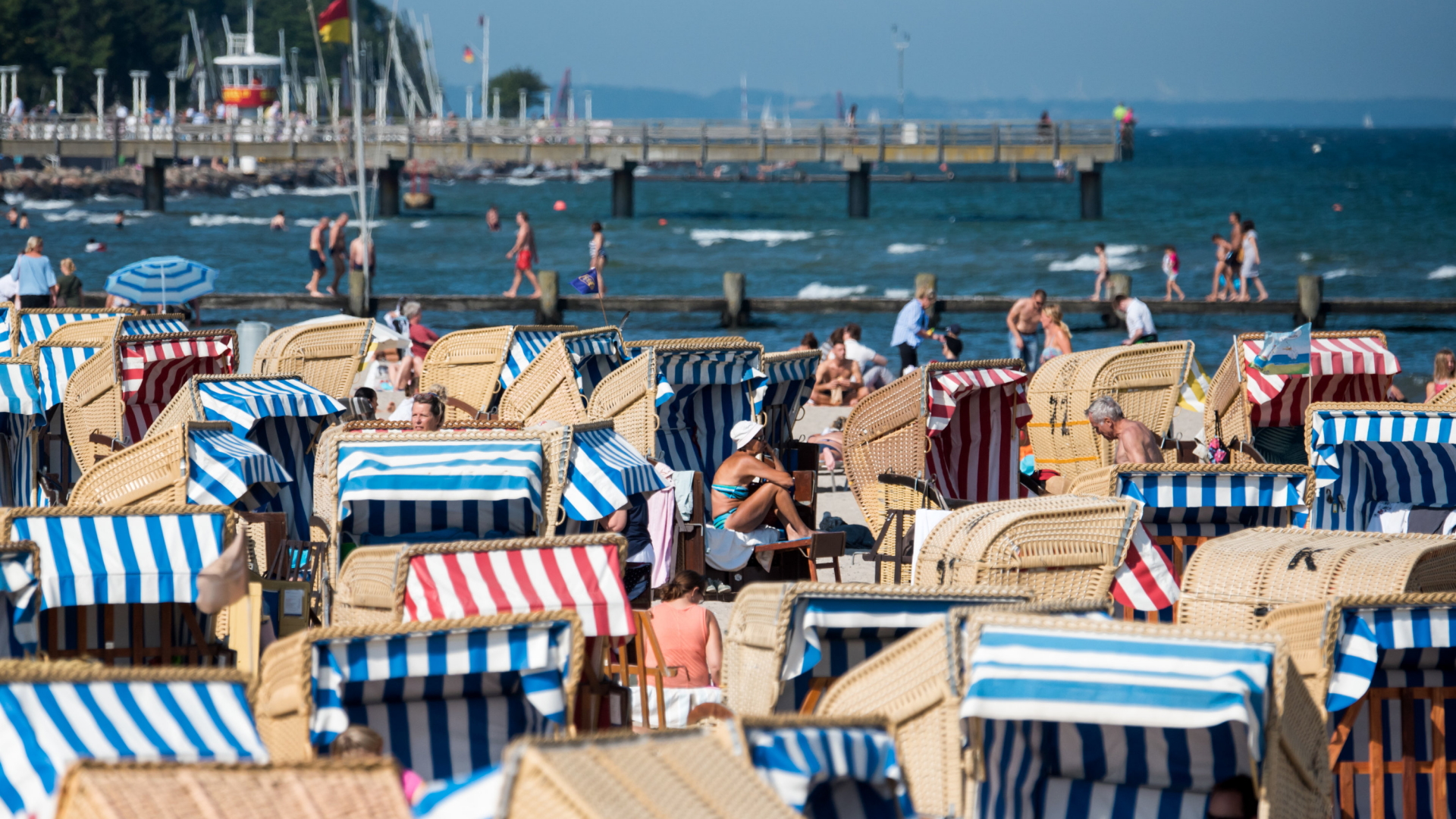 Menschen genießen in Strandkörben am Ostseestrand in Travemünde die Sonne. (Archivbild vom 25.06.2019) | dpa