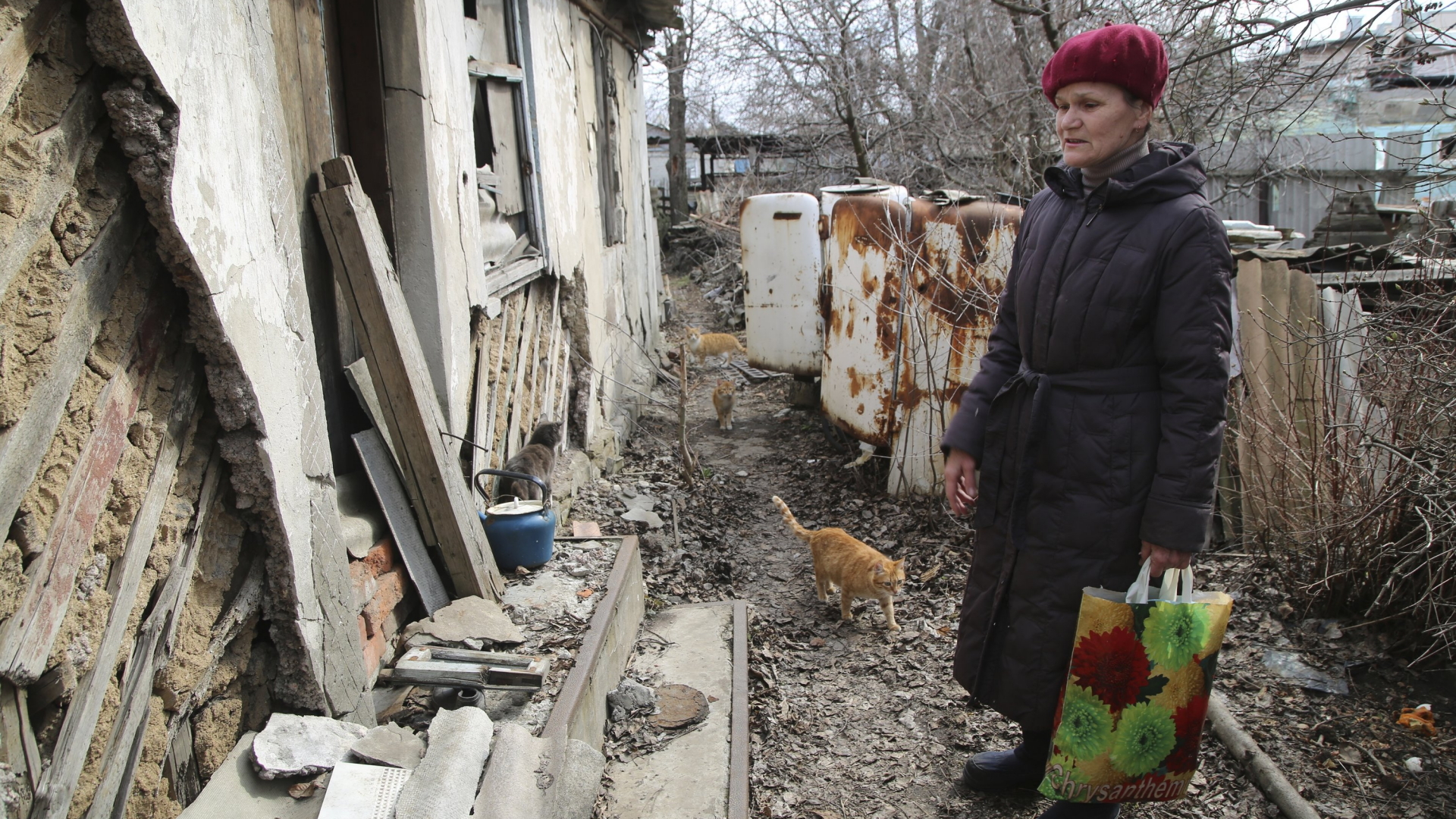 Eine ältere Frau sucht in ihrem zerstörten Haus in Donezk nach Habseligkeiten (9.4.2021). | AP