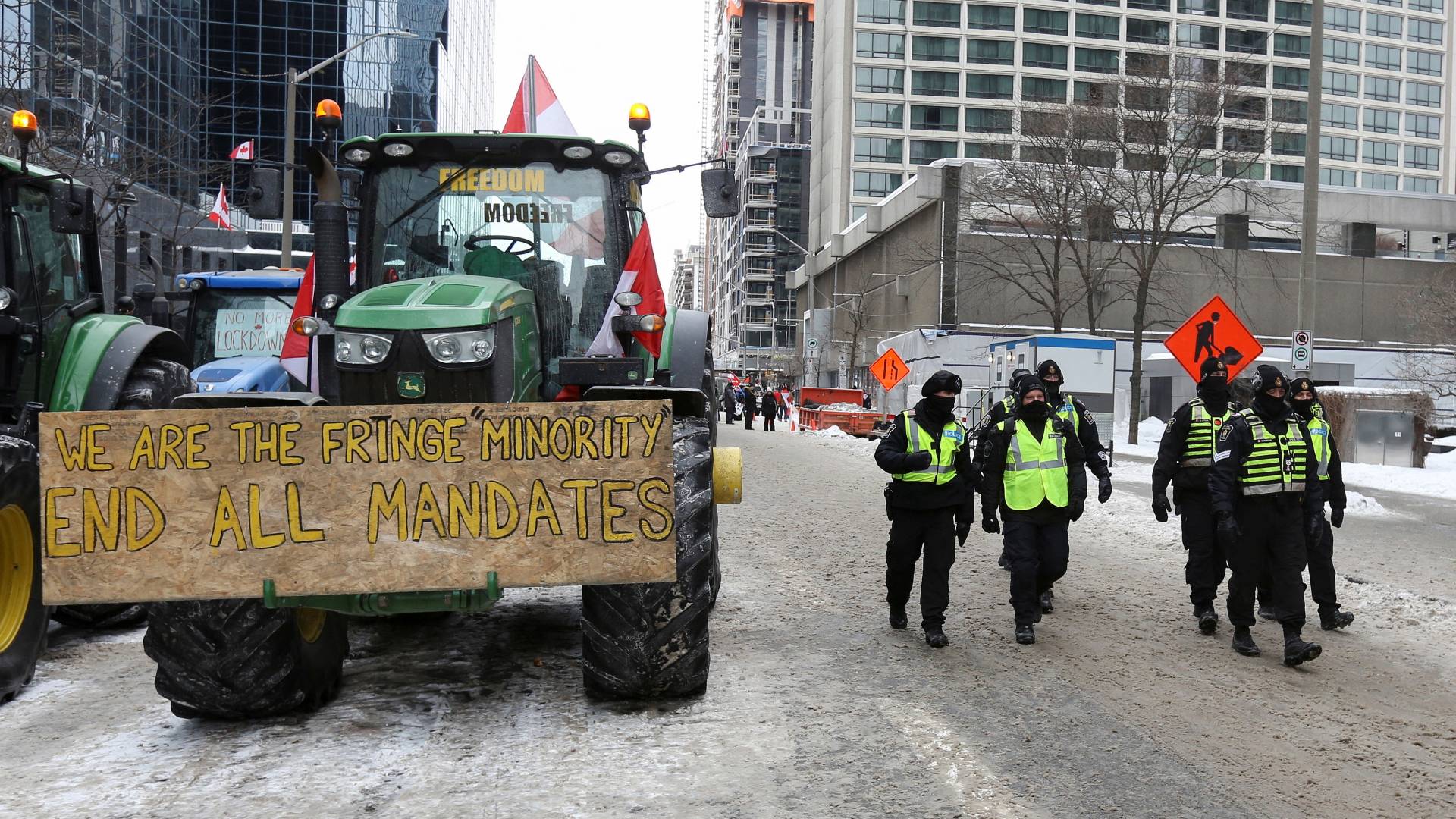 Ein Schild mit der Forderung alle Corona-Maßnahmen zu beenden auf einem Traktor in der kanadischen Hauptstadt Ottawa und daneben patrouillieren Polizisten. | REUTERS