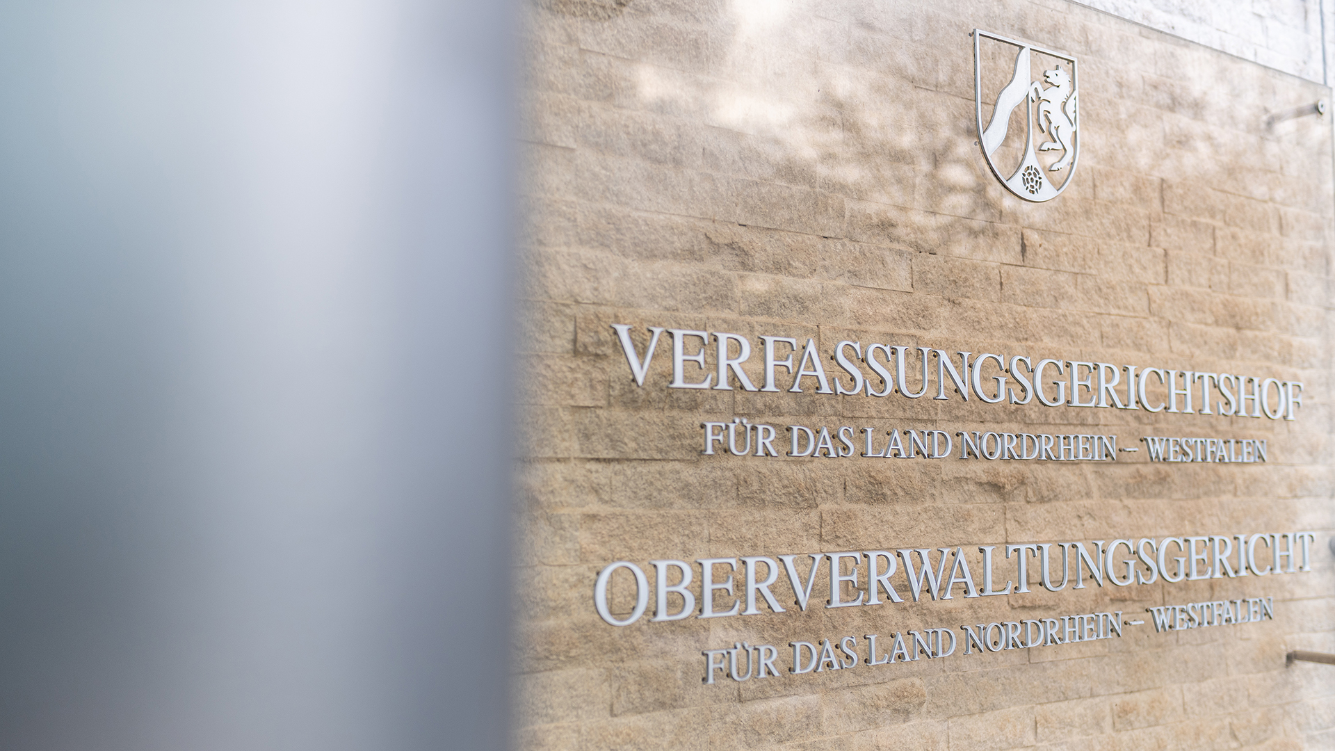 An der Außenfassade stehen auf einem Schild die Schriftzüge: Verfassungsgerichtshof für das Land Nordrhein-Westfalen und Oberverwaltungsgericht für das Land Nordrhein-Westfalen. | dpa