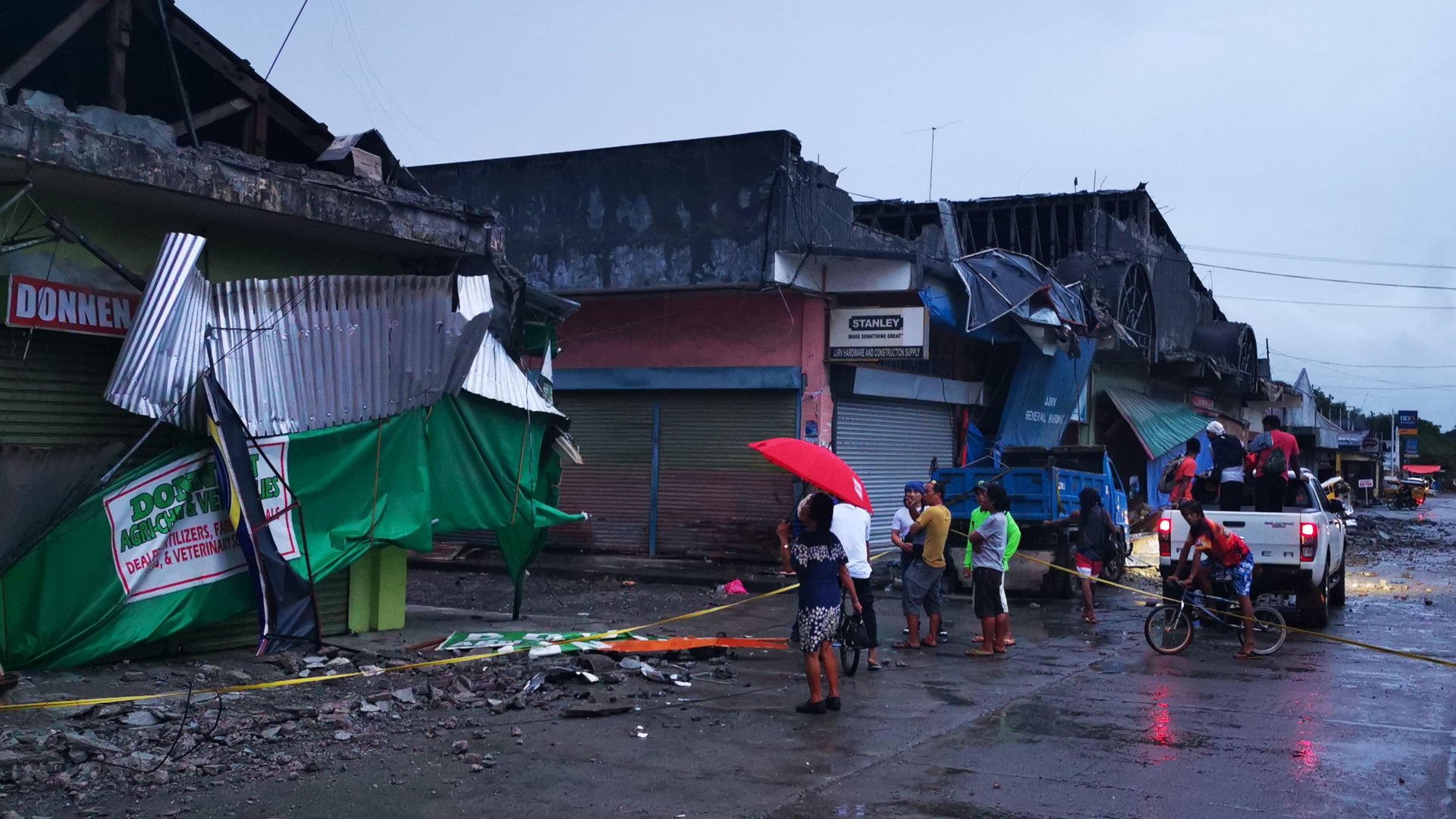 Bewohner stehen in Padada vor einem eingestürzten Gebäude | AFP