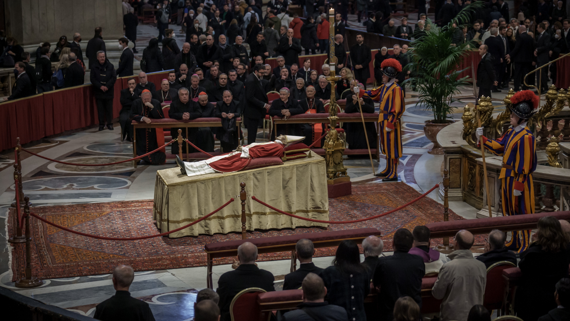 Besucher knien und stehen rund um den aufgebahrten Papst Benedikt XVI. | dpa