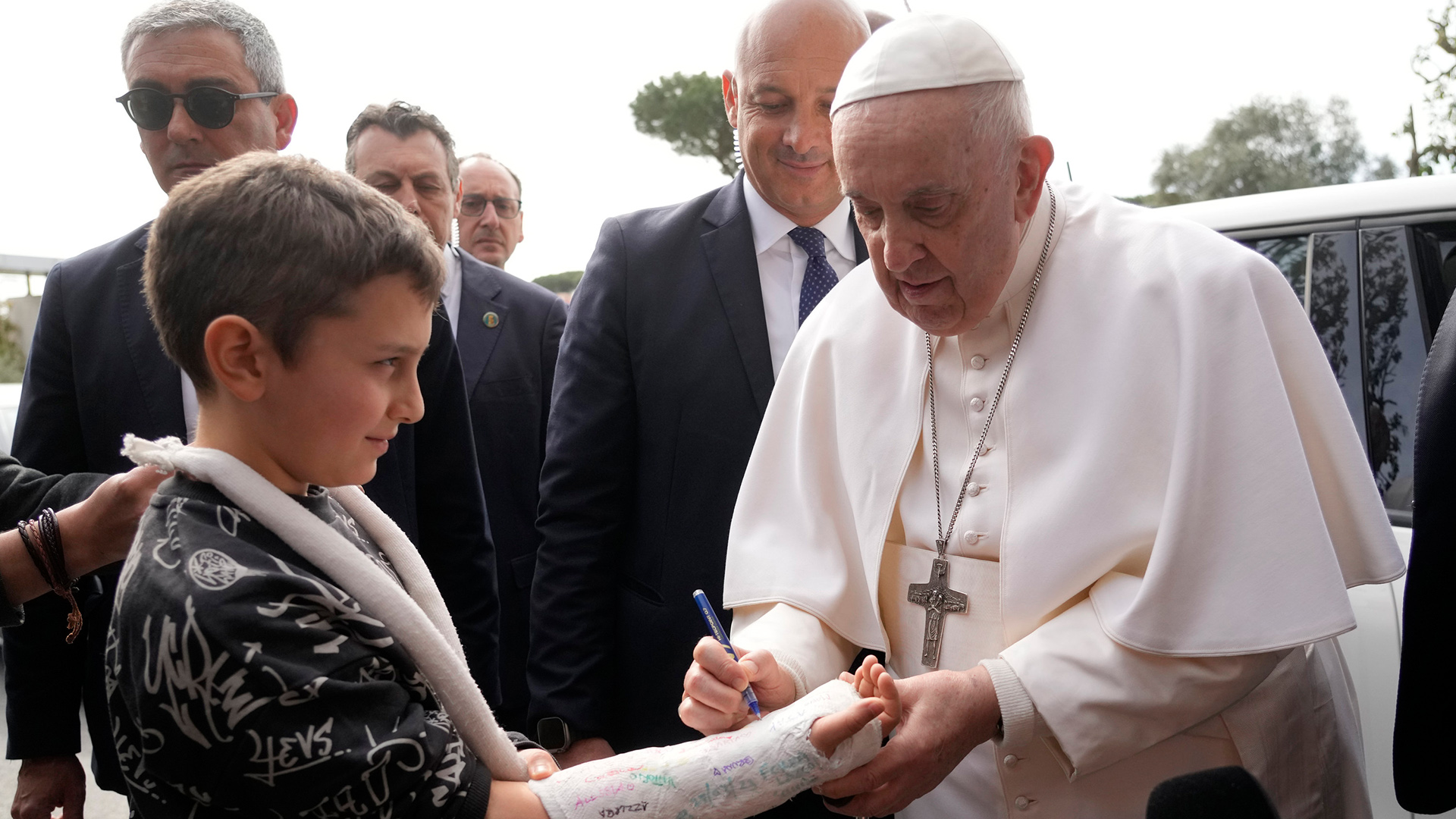 Papst Franziskus unterschreibt auf dem Gipsarm eines Jungen beim Verlassen des Krankenhauses.