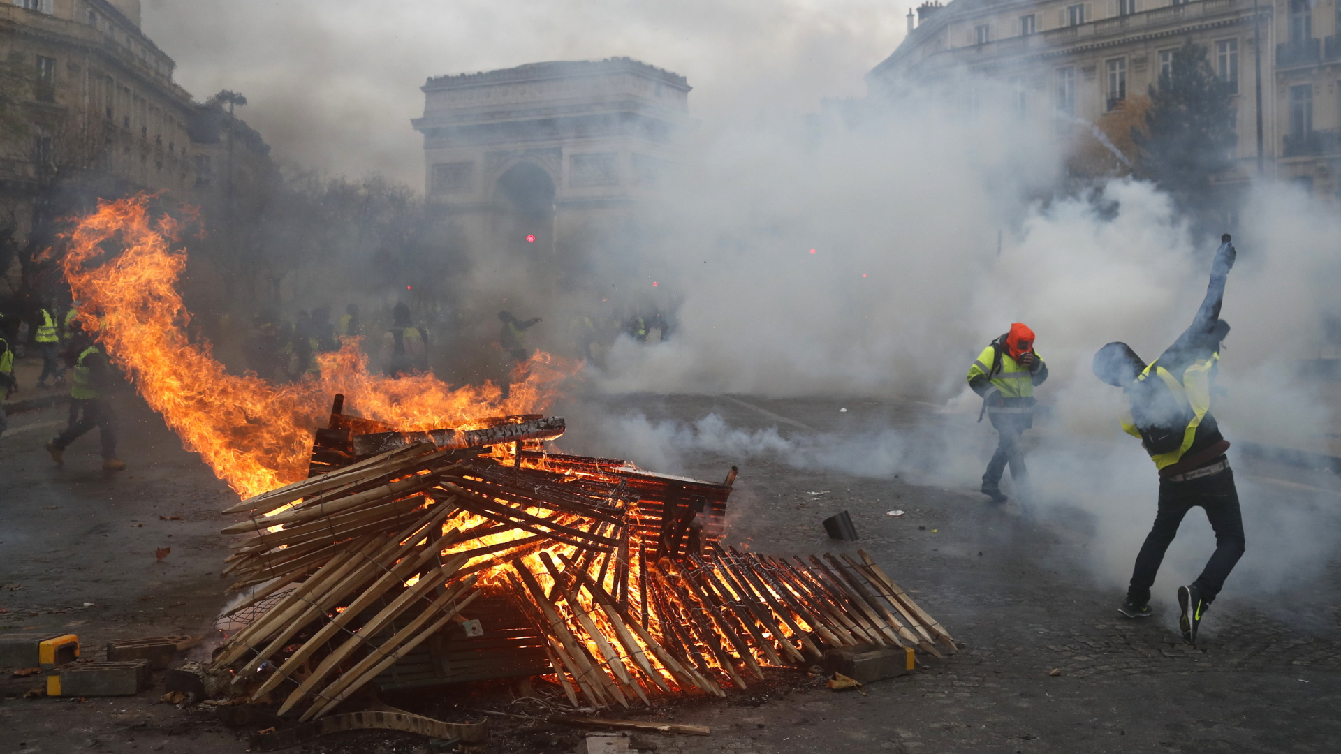 Ein Demonstrant in gelber Weste steht in Paris vor einer brennenden Barrikade | Bildquelle: AP