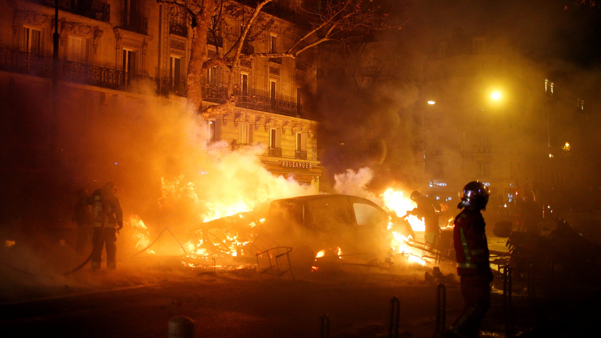 Feuerwehrleute stehen vor einem brennenden Auto. | Bildquelle: REUTERS