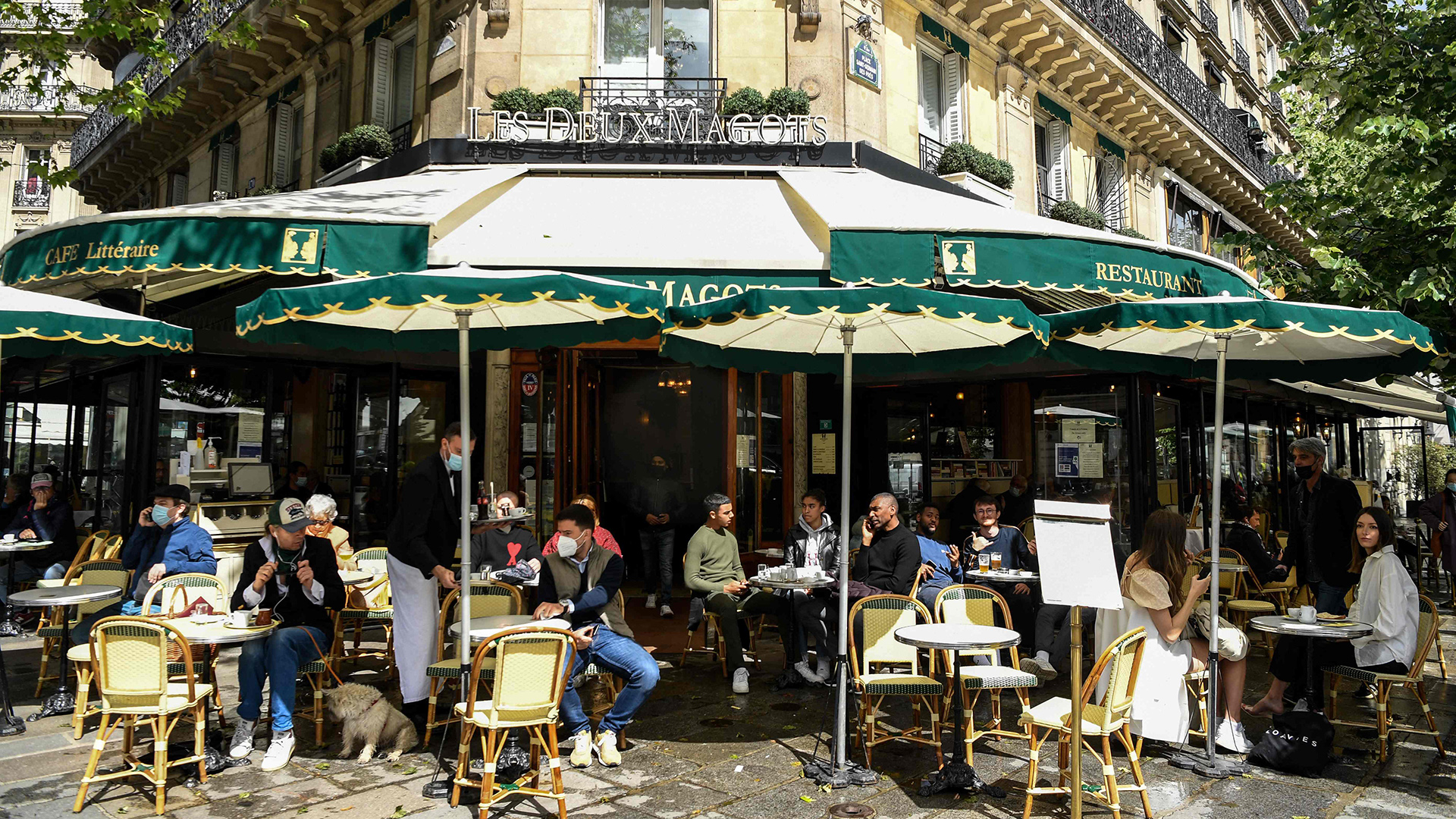 Menschen sitzen im Außenbereich eines Cafés. | AFP