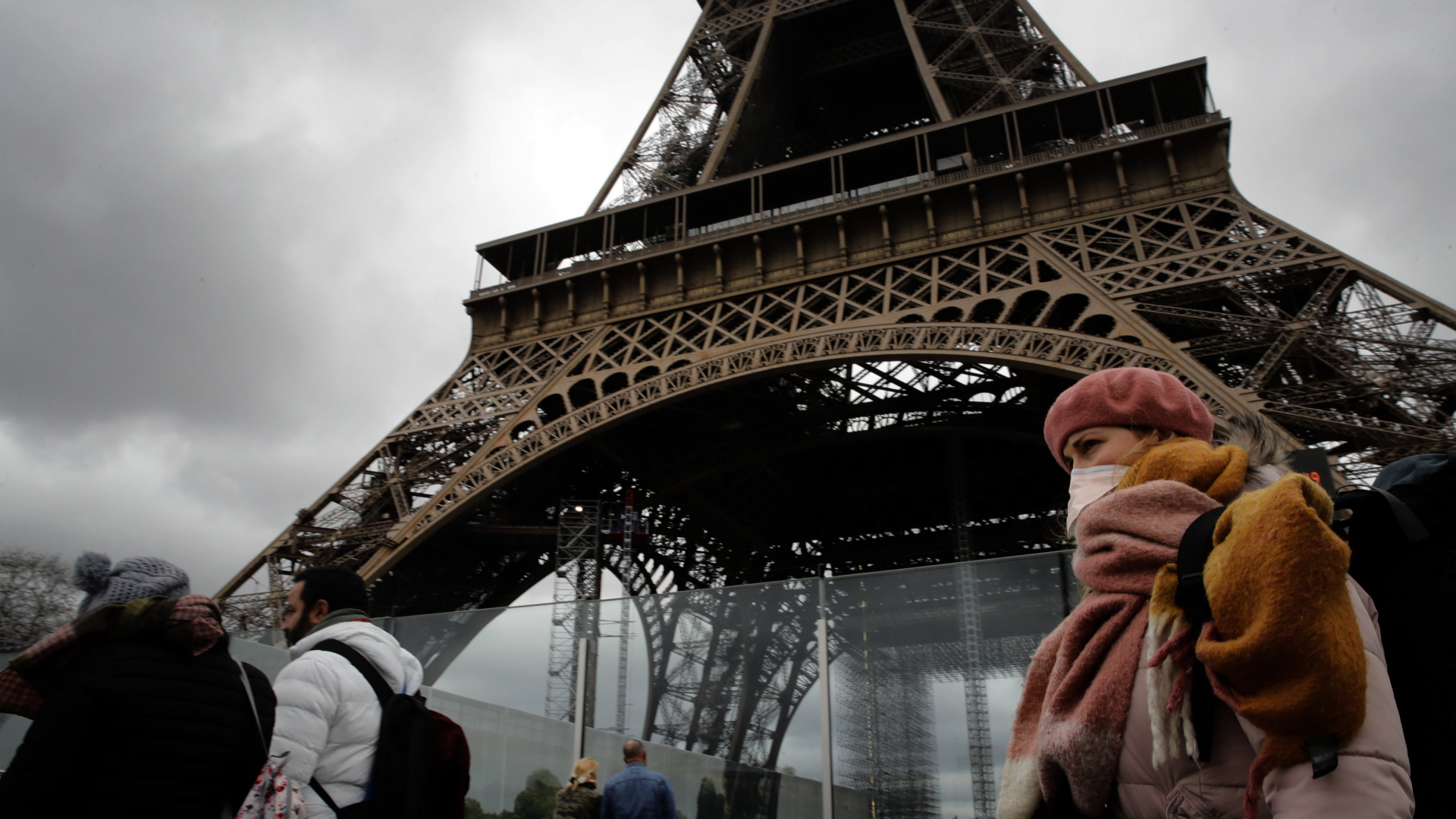 Passanten mit Mundschutz gehen am Eiffelturm in Paris vorbei. | AP