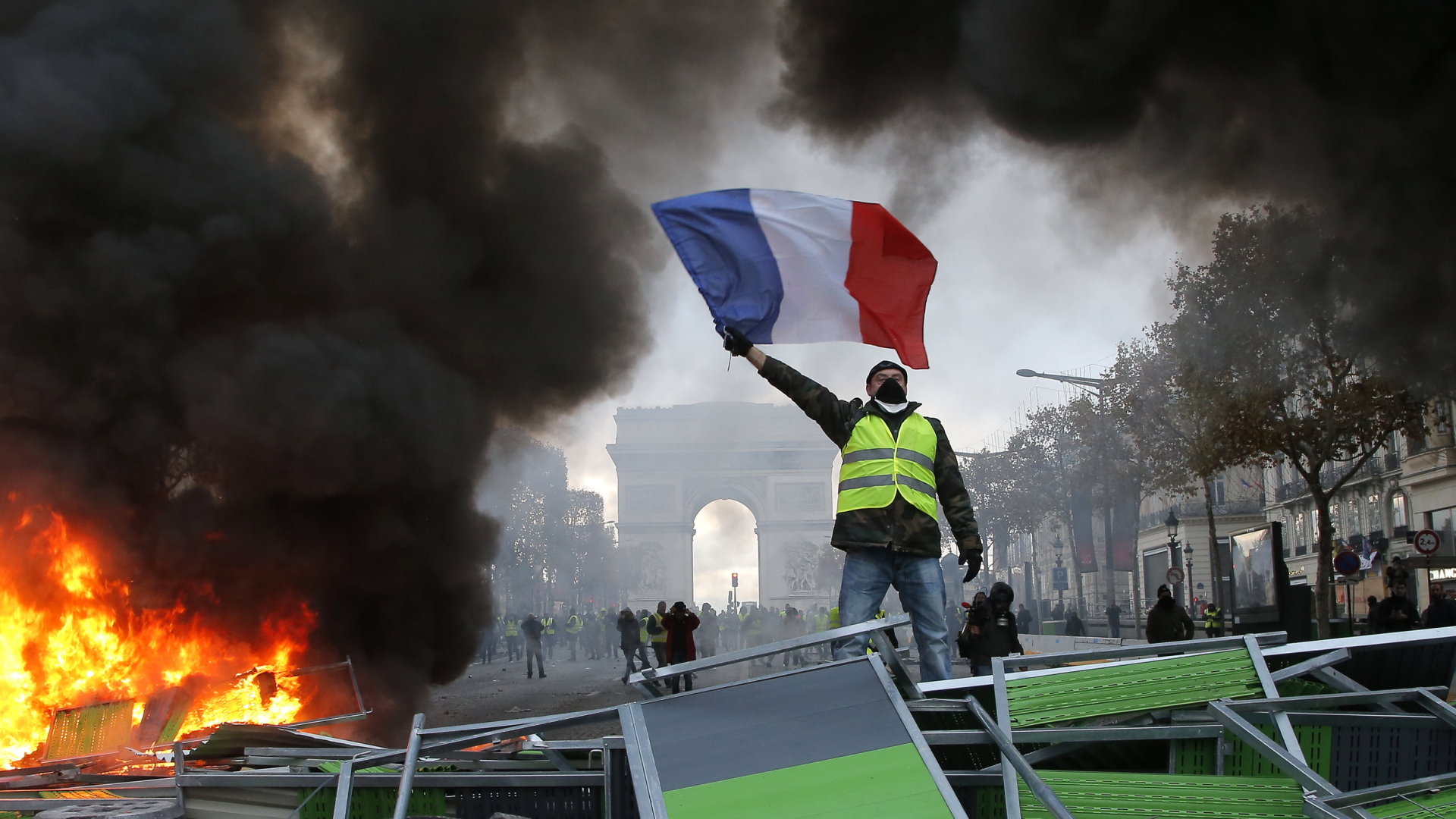 In Paris schwenkt ein Anhänger der "Gelbwesten" die französische Flagge.  | Bildquelle: AP