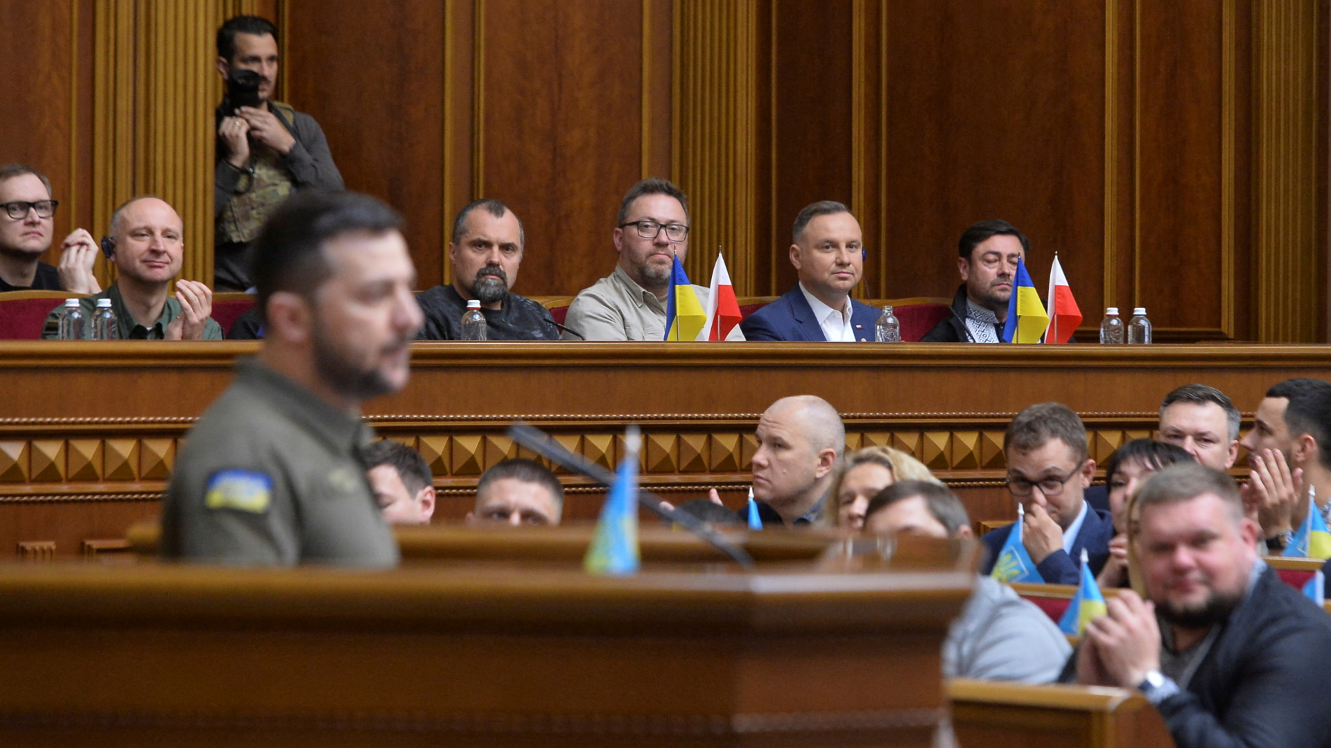Eine Sitzung des Parlaments der Ukraine im Mai 2022. Im Vordergrund verschwommen Wolodymyr Selenskyj, im Hintergrund Andrzej Duda.