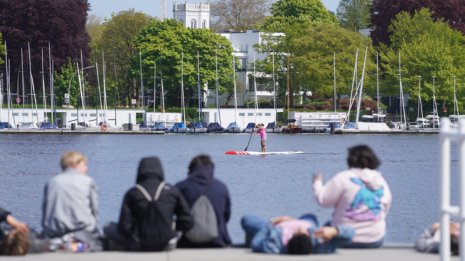 Passanten genießen das sonnige Wetter an der Außenalster in Hamburg. | dpa
