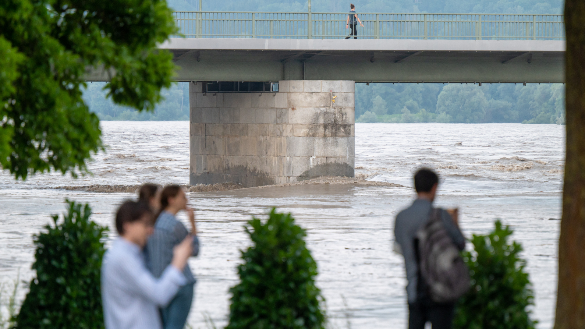 Passanten stehen Abend am teilweise überfluteten Ufer des Inn in Passau
