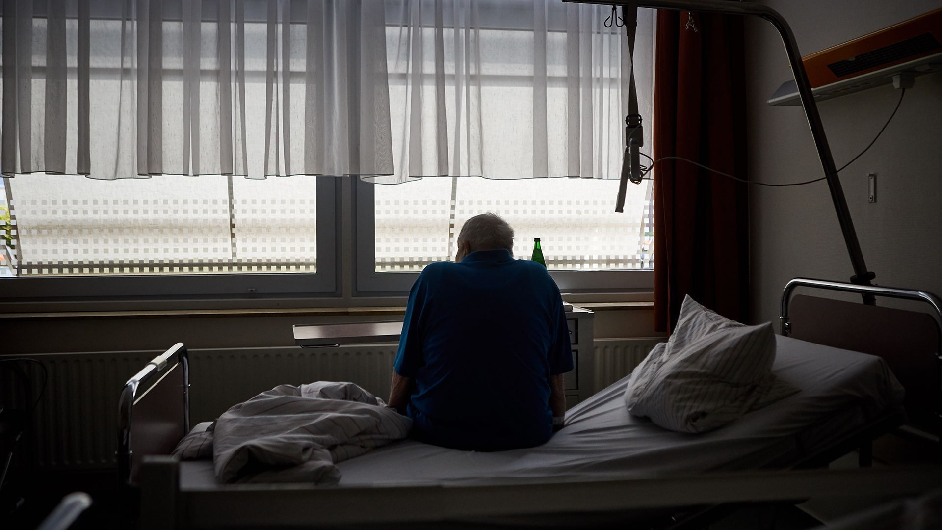 Ein Patient sitzt auf einem Bett in einem Krankenhaus.